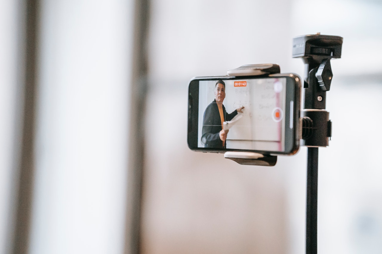 A man filming a video on his smartphone for a marketing campaign for his manufacturing business