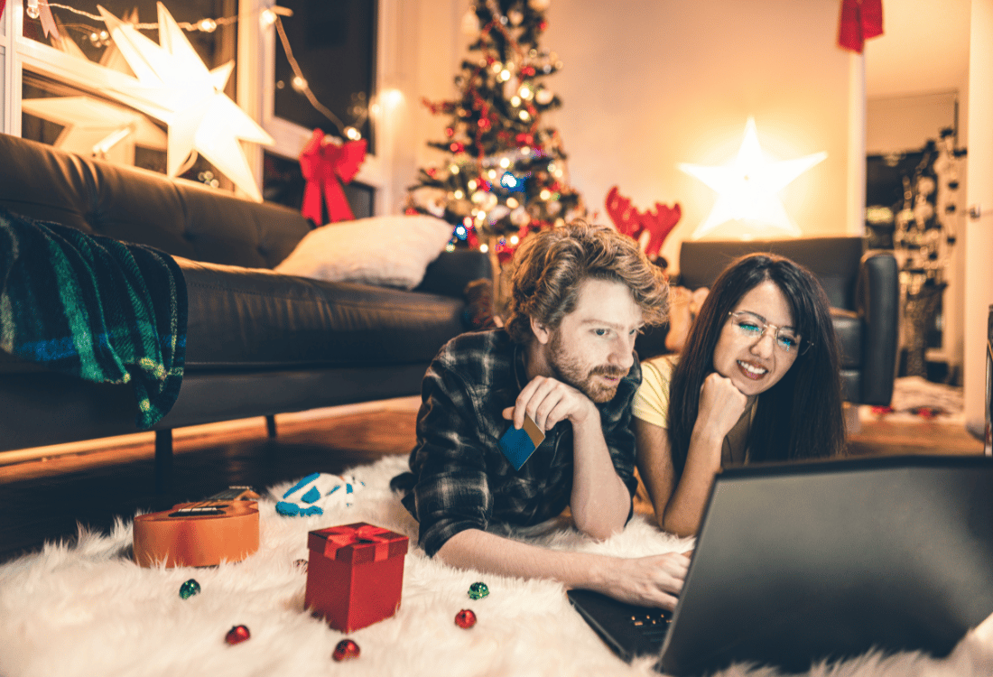 Two people looking at a laptop in a room decorated for Christmas