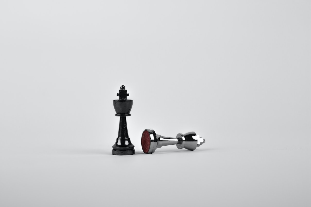 Two chess pieces with one fallen over owned by a business owner that has not developed their business with the times and the second still standing owned by a business owner who has a evolving marketing strategy