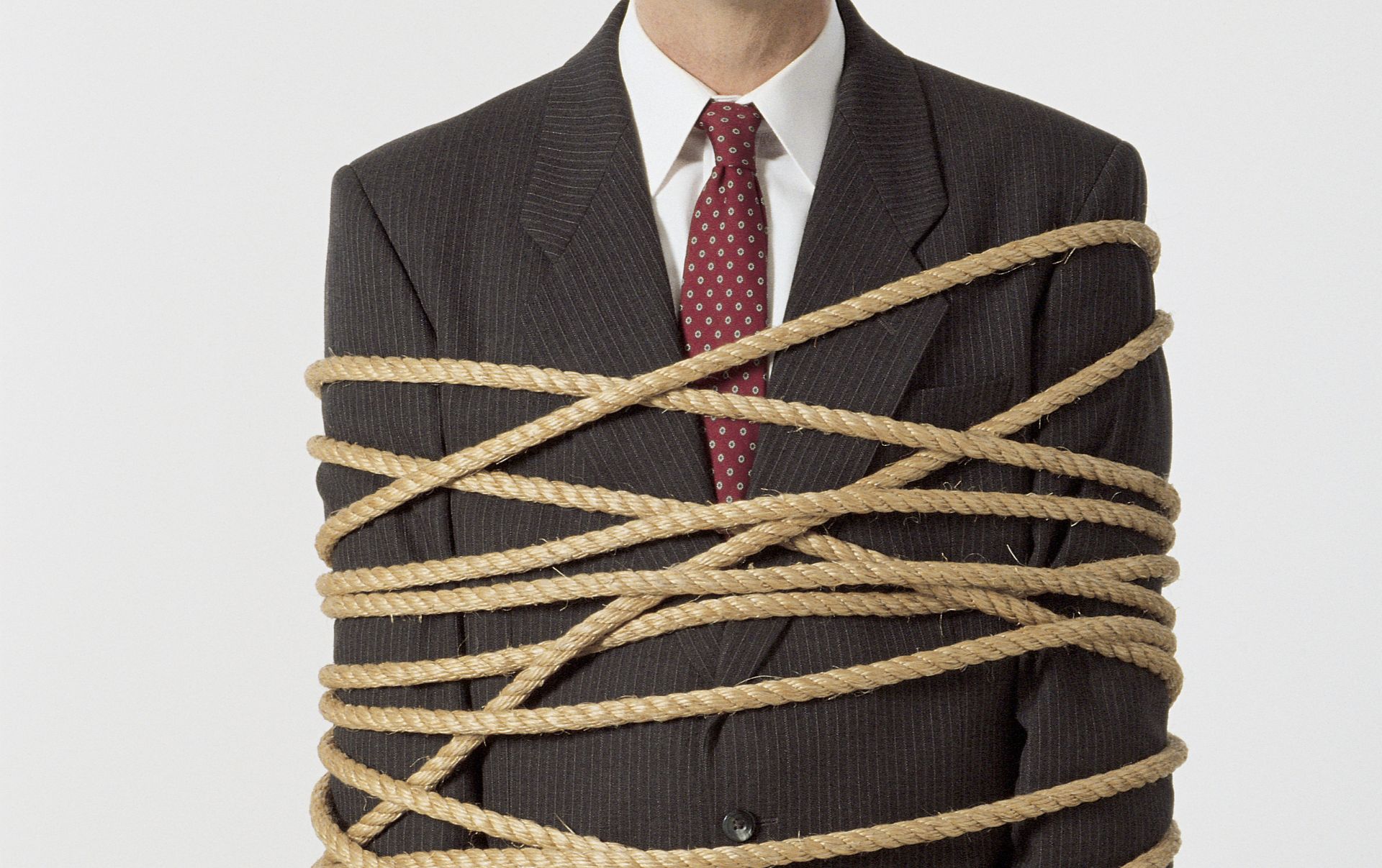 A business man in a suit tied up with rope as he tries to move his website to another platform and hosting company.