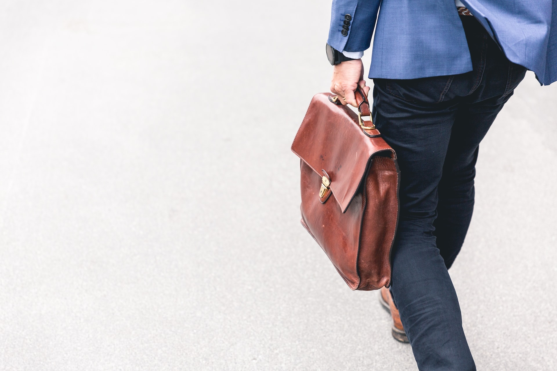 A business owner in a smart suit, holding a satchel bag, walking to a meeting with an ideal customer to propose offers and incentives which will help him make a sale
