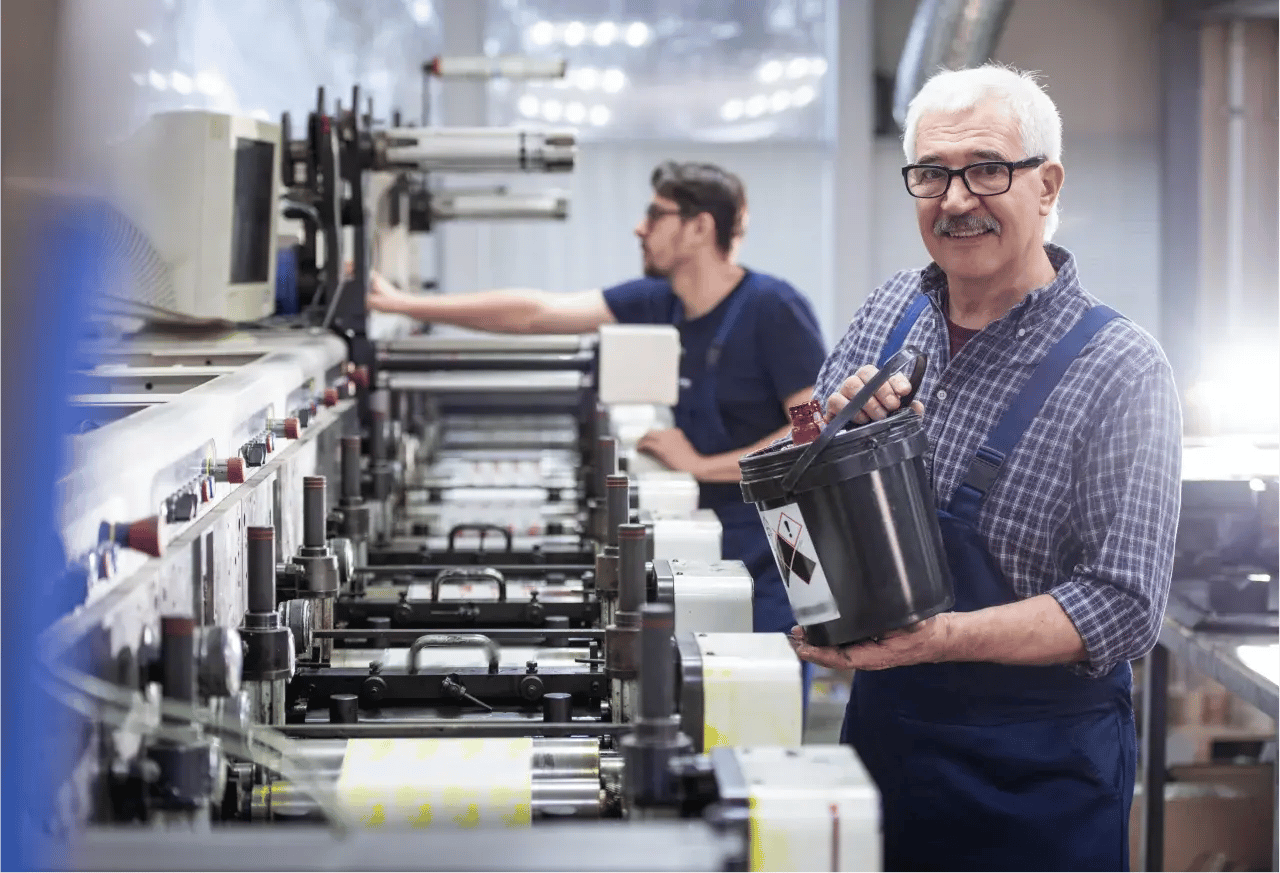 Worker pours ink into industrial printer.