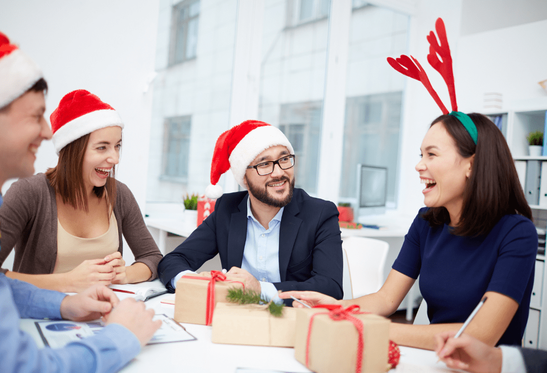 Marketing team wearing Christmas hats brainstorming festive inbound marketing campaigns in a cheerful office setting.