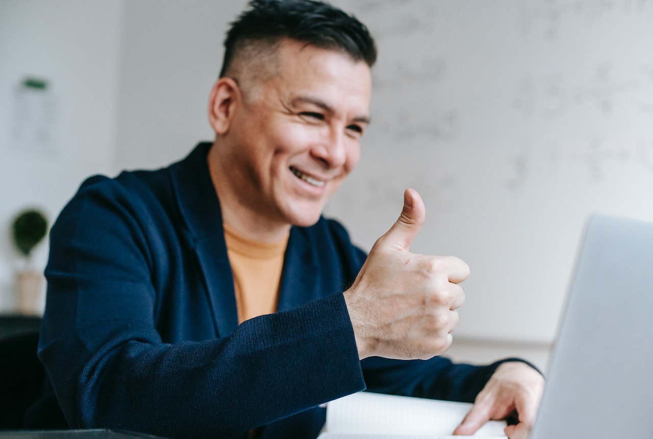 A businessman giving a thumbs up during a client call as he uses HubSpot's CRM to help better his customer and client relationships