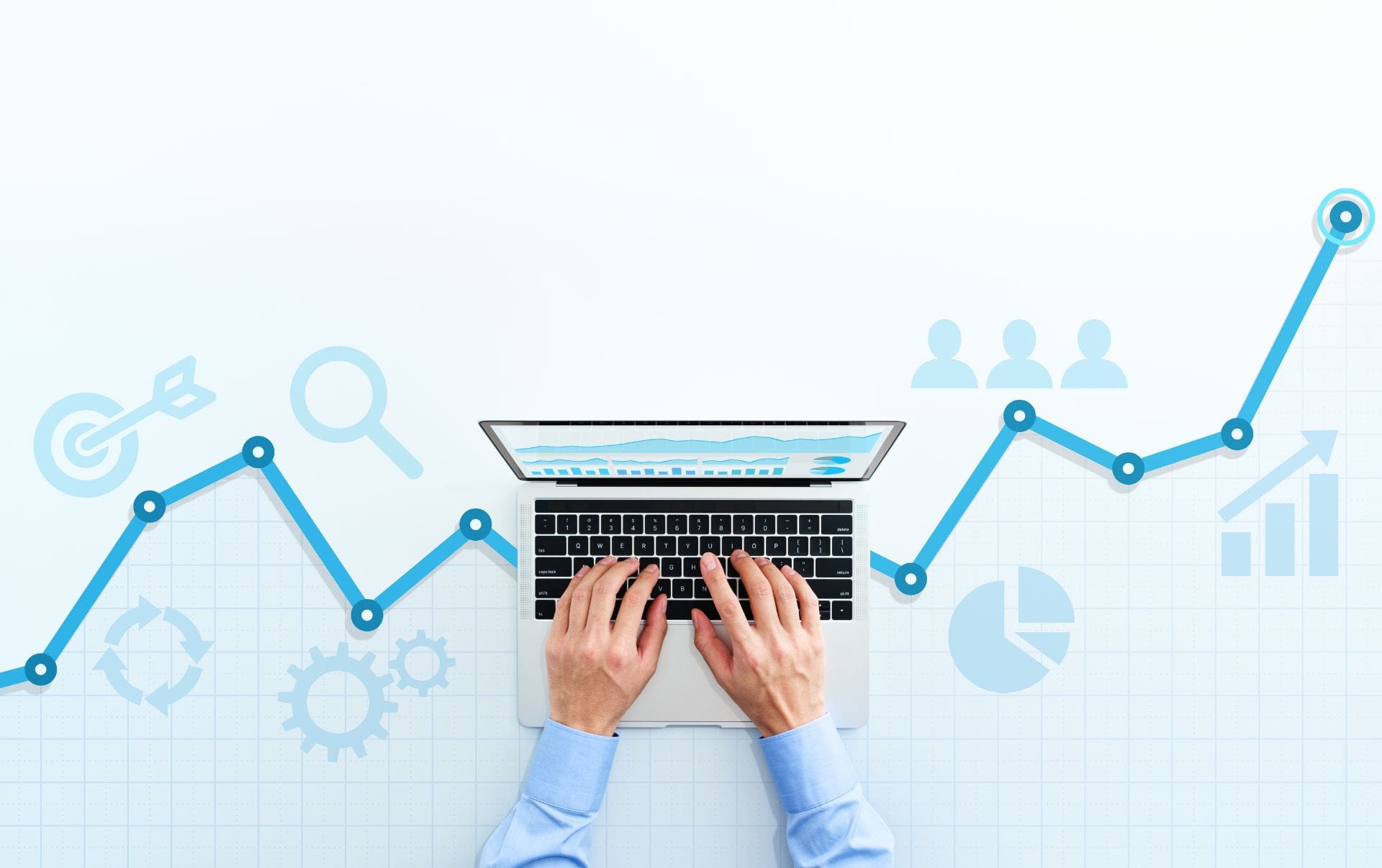 A business owner typing on his laptop checking his business' HubSpot analytics and reporting tools to see how his customers have grown as a raising line chart grows across his desk under his laptop