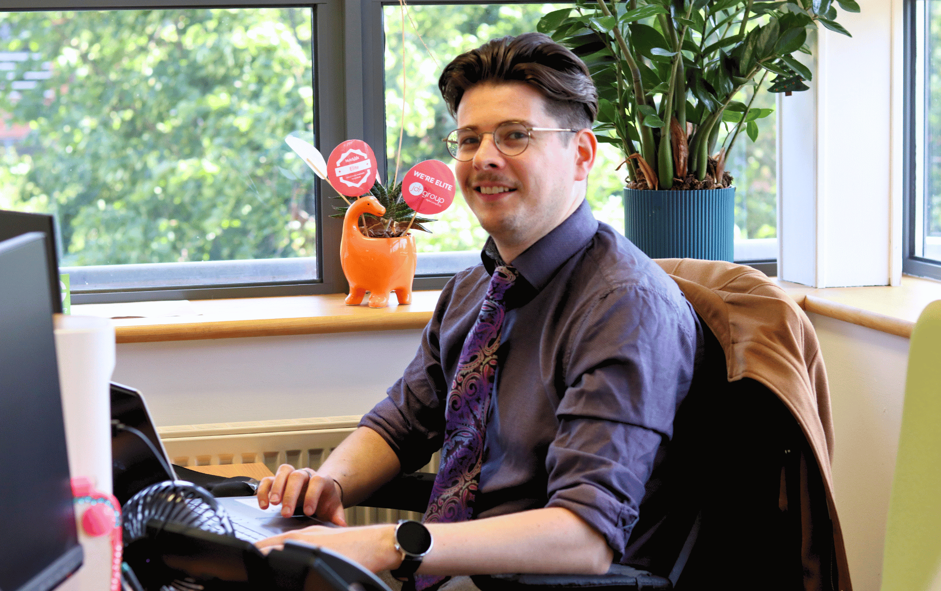 John-James at JDR smiling at the camera while working at his desk, planning a successful SEO content strategy for 2025.