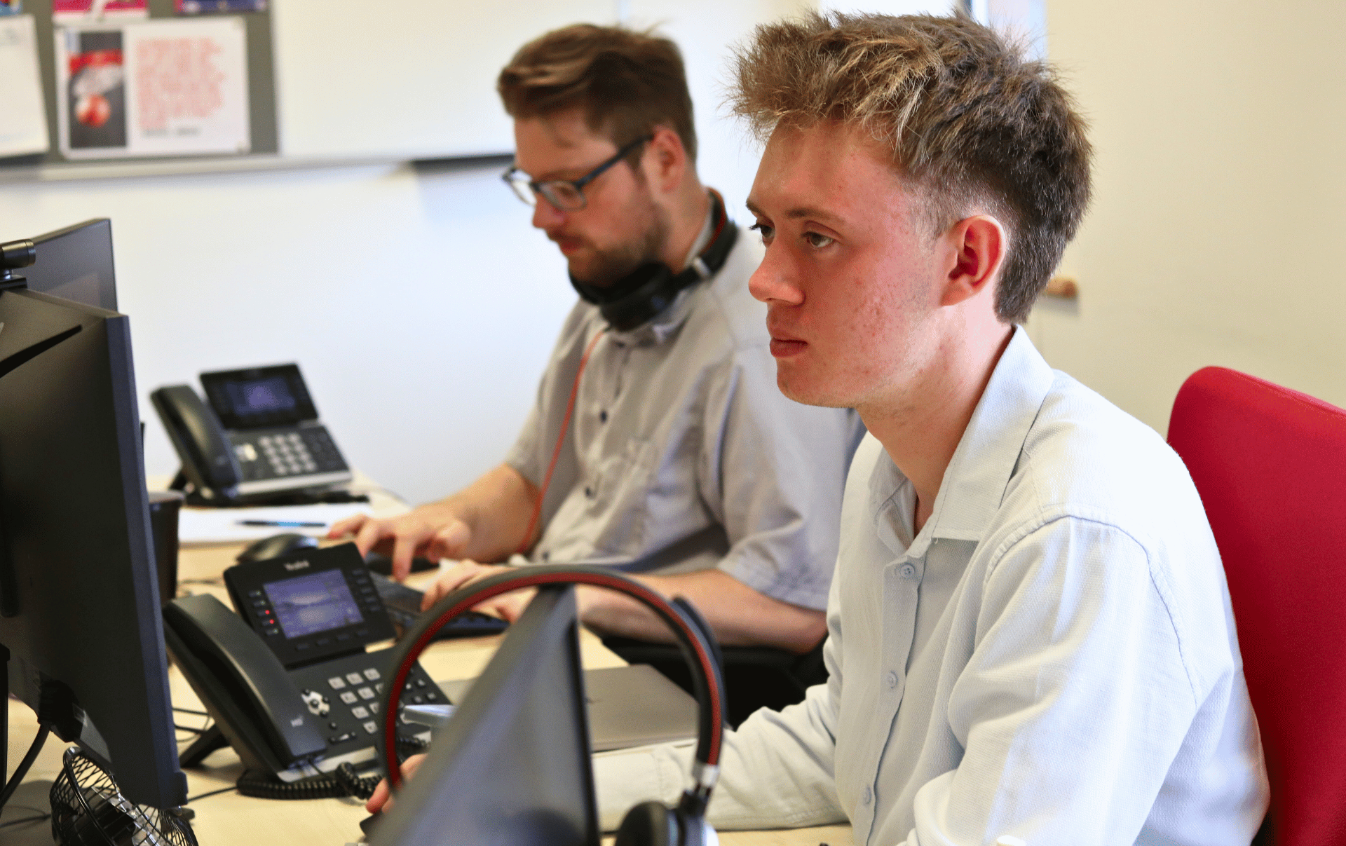 Tom at JDR looking attentively at his screen, with Rhys working on his laptop in the foreground, both focused on developing a successful SEO content strategy for 2025.