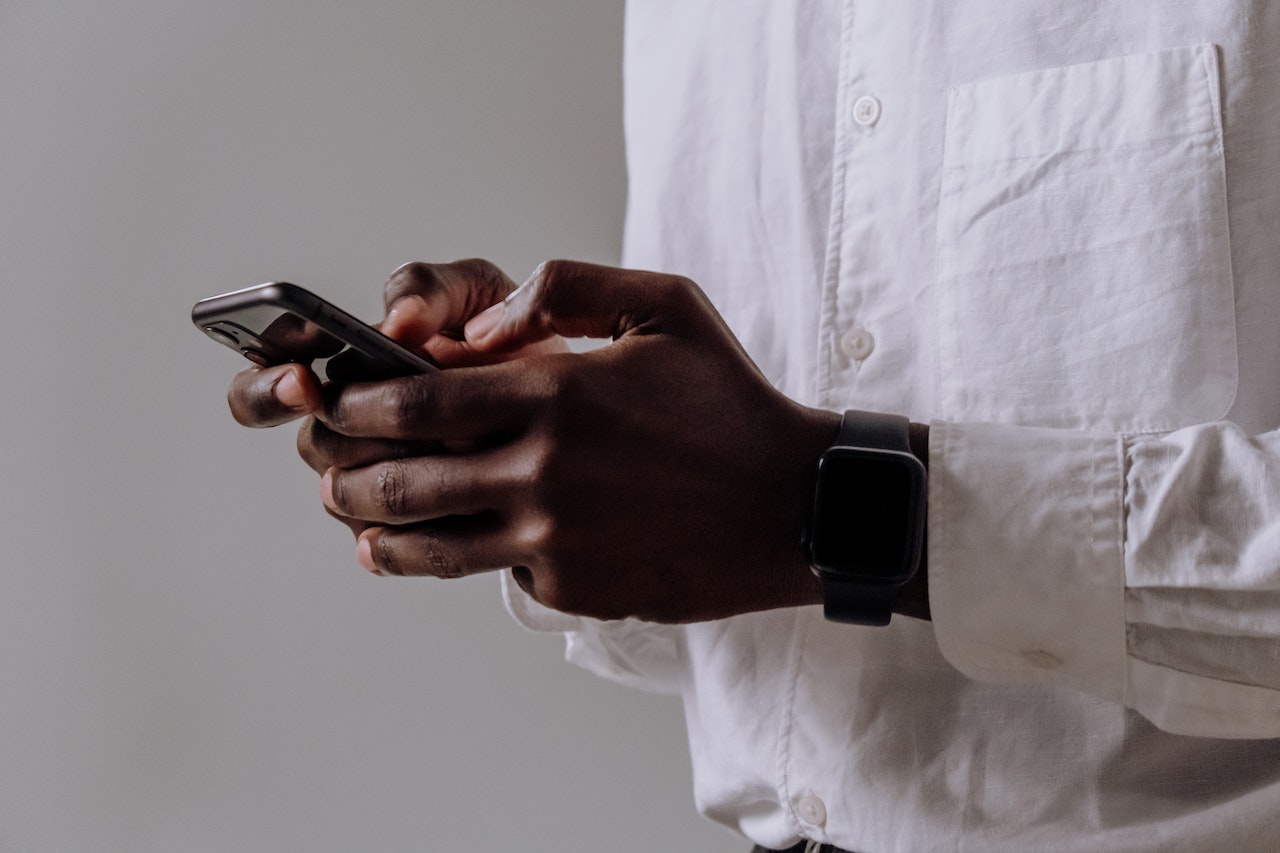 A businessman in a dress shirt on his smartphone using social media for his business which is successfully growing through his social media marketing strategy 