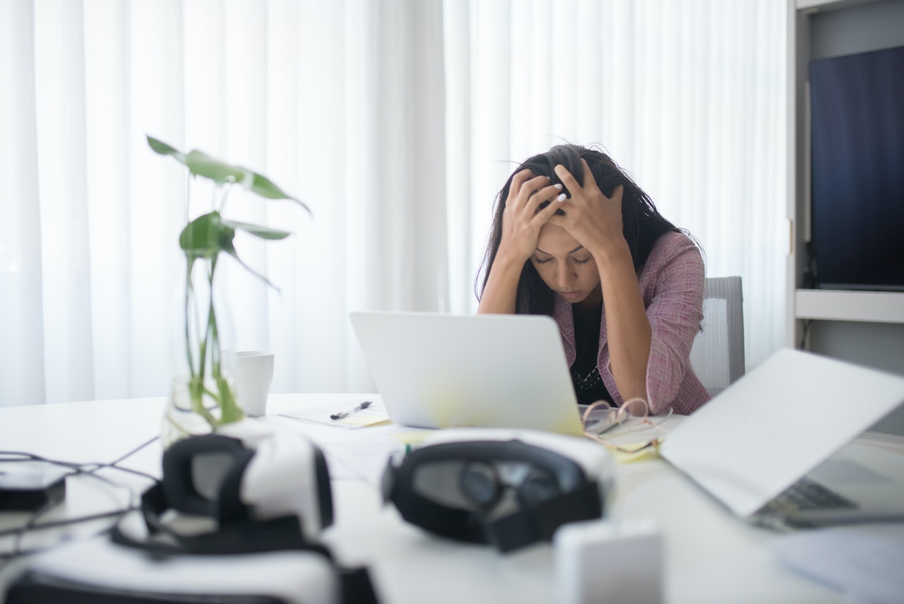 A business women holding her head in frustration as her small business has just experienced a website hack