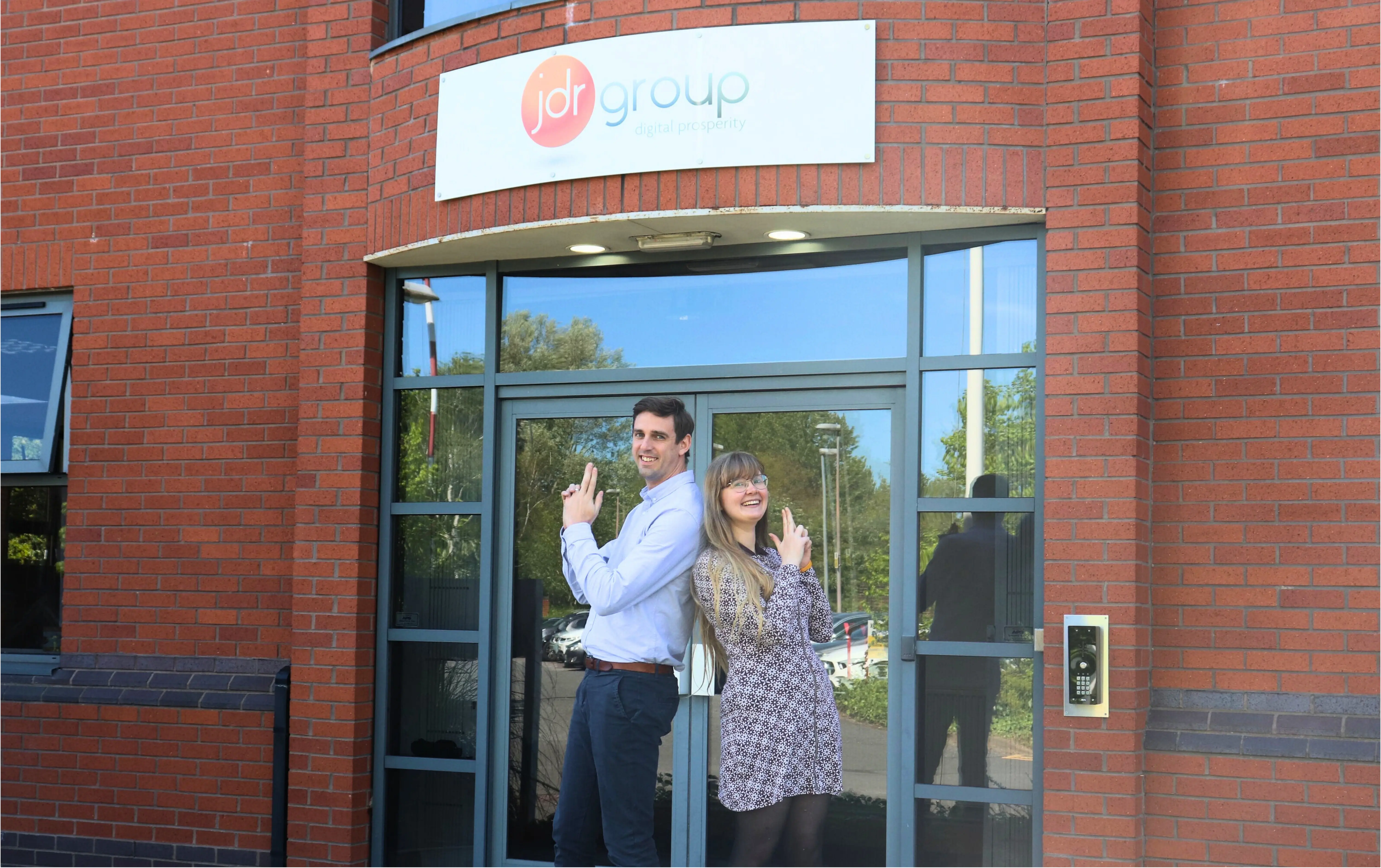 Andy and Emma from JDR standing back-to-back outside the JDR office, smiling and posing ahead of the HubSpot AI webinar.