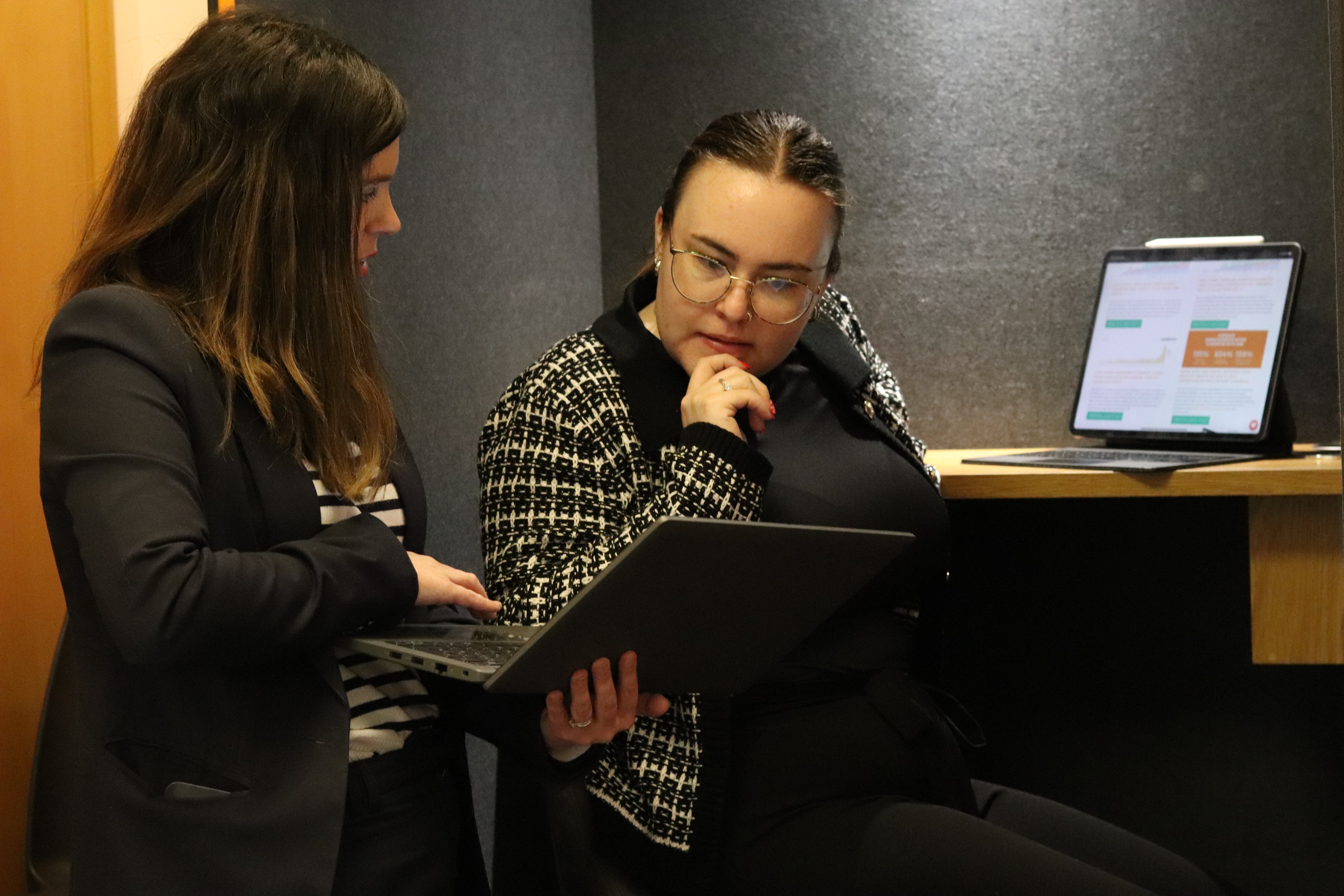 Shirley and Ellis gathered around a laptop discussing something and looking focused.