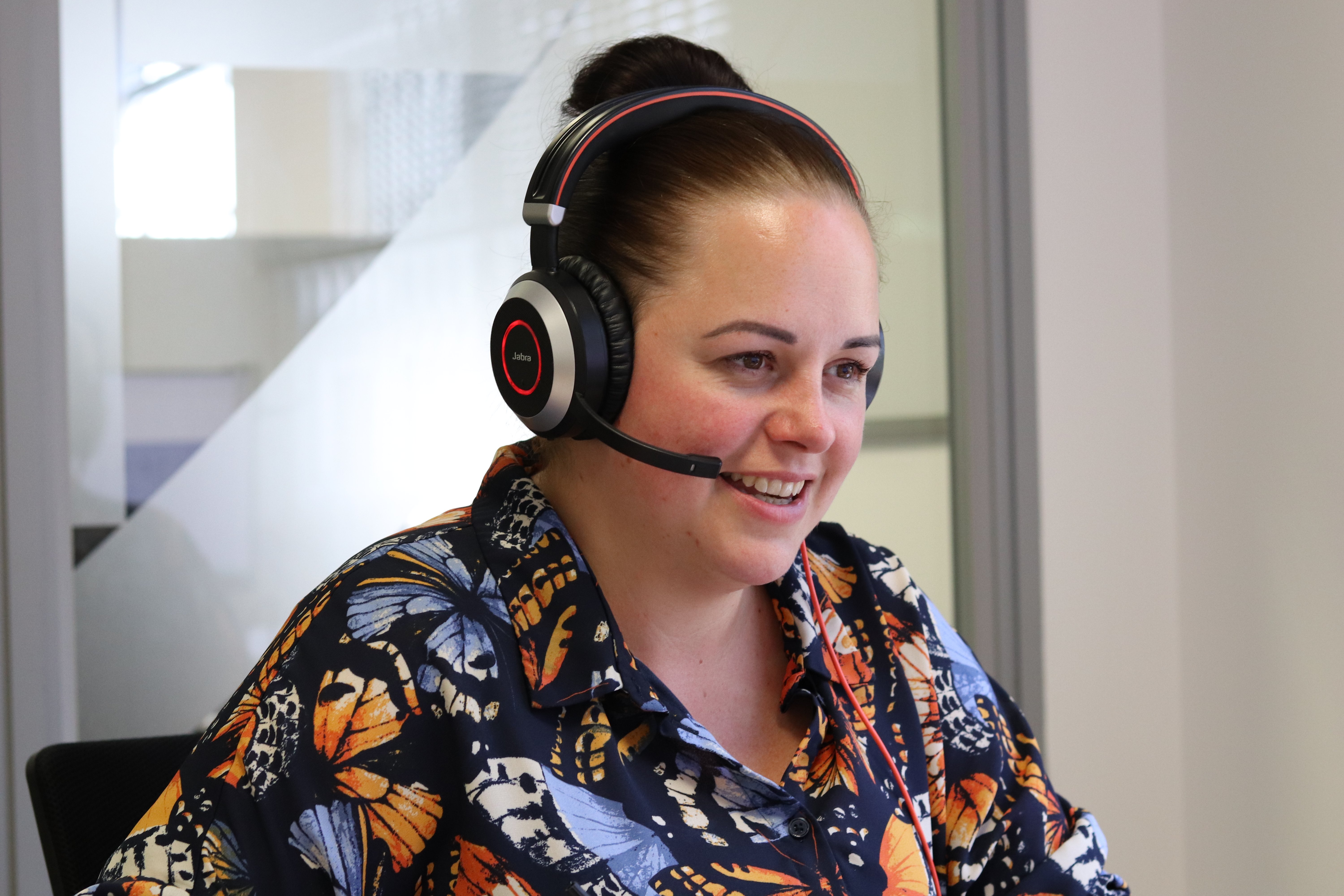 Ann with her headset on in a butterfly pattern shirt on call with a prospect while using CPQ software.