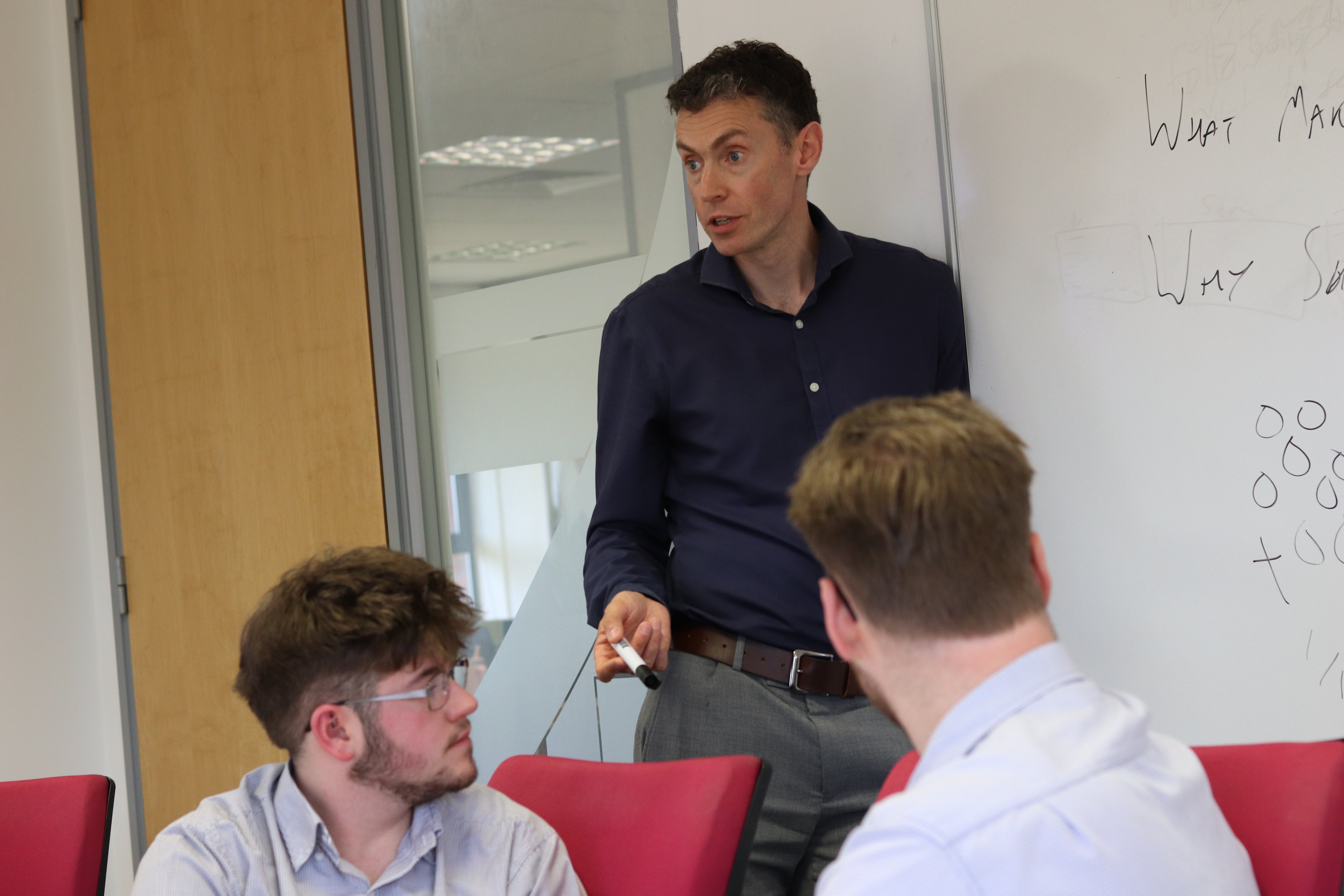 Will holding a whiteboard pen, leading a meeting to others about Hubspot.