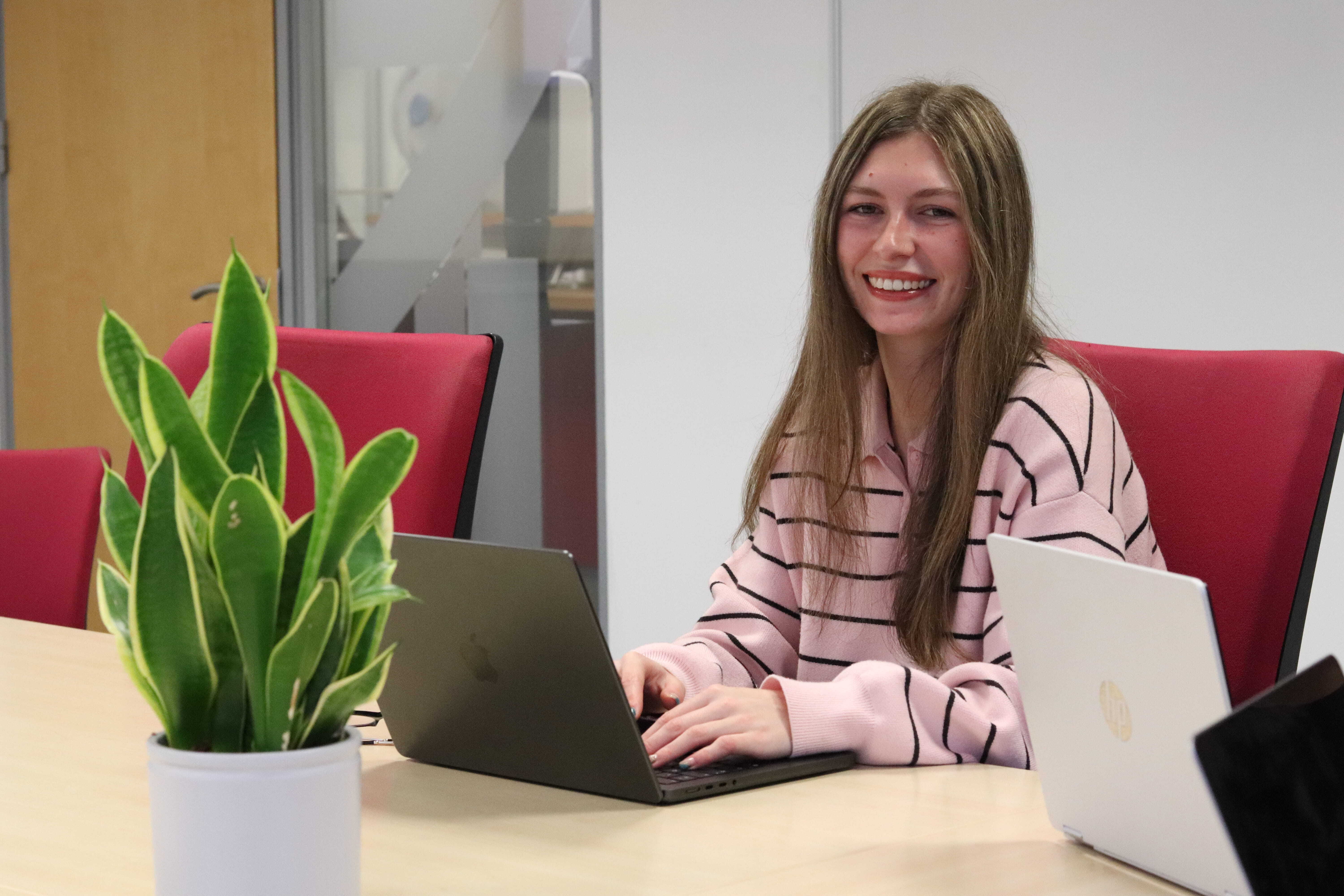 Sophie smiling while working on her laptop, discussing effective social media strategies.