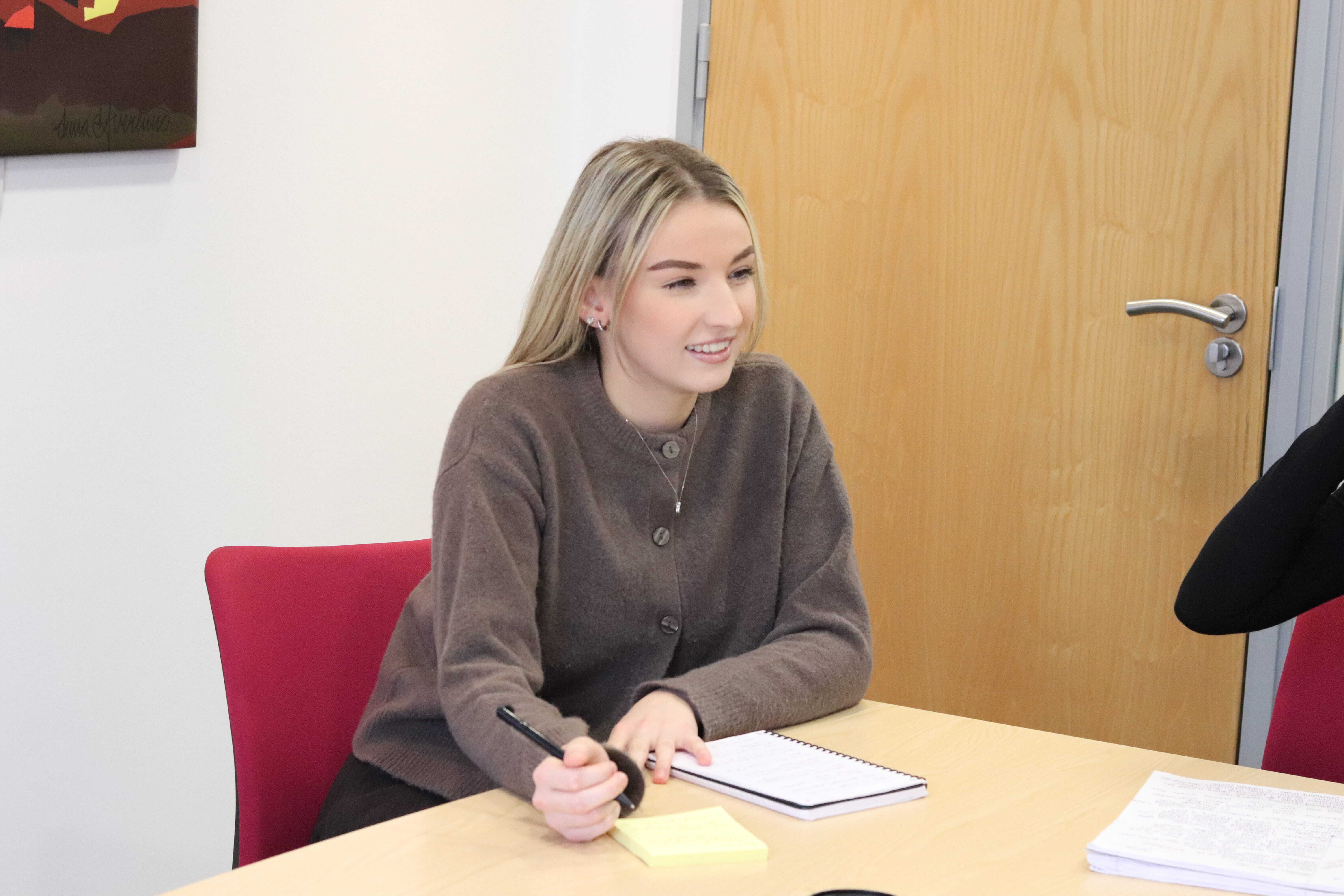 Emily writing with a pen on her note pad while smiling and discussing WordPress hosting.
