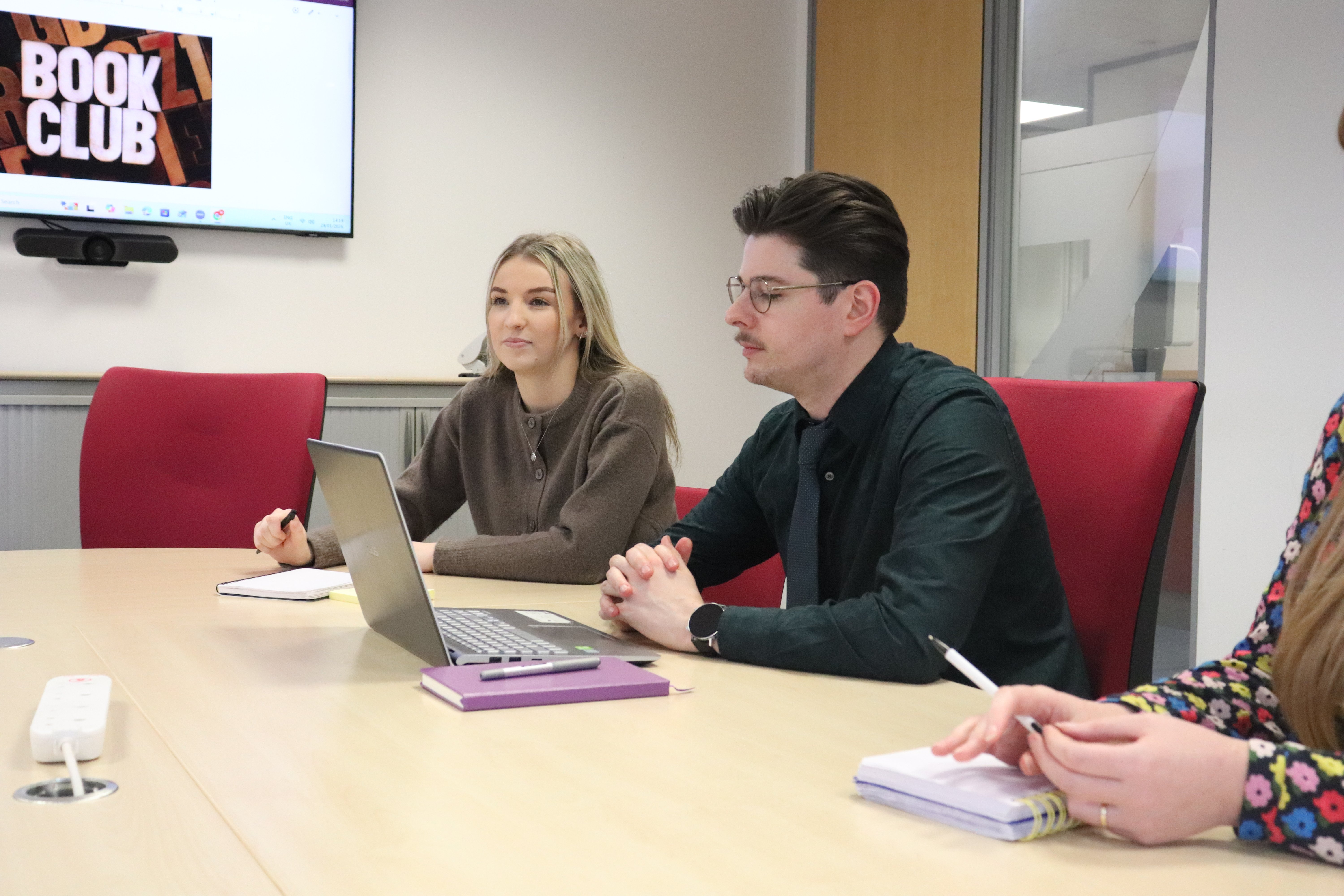 Emily and John-James with their notepads and laptops looking focused in a meeting about hubspot pricing.