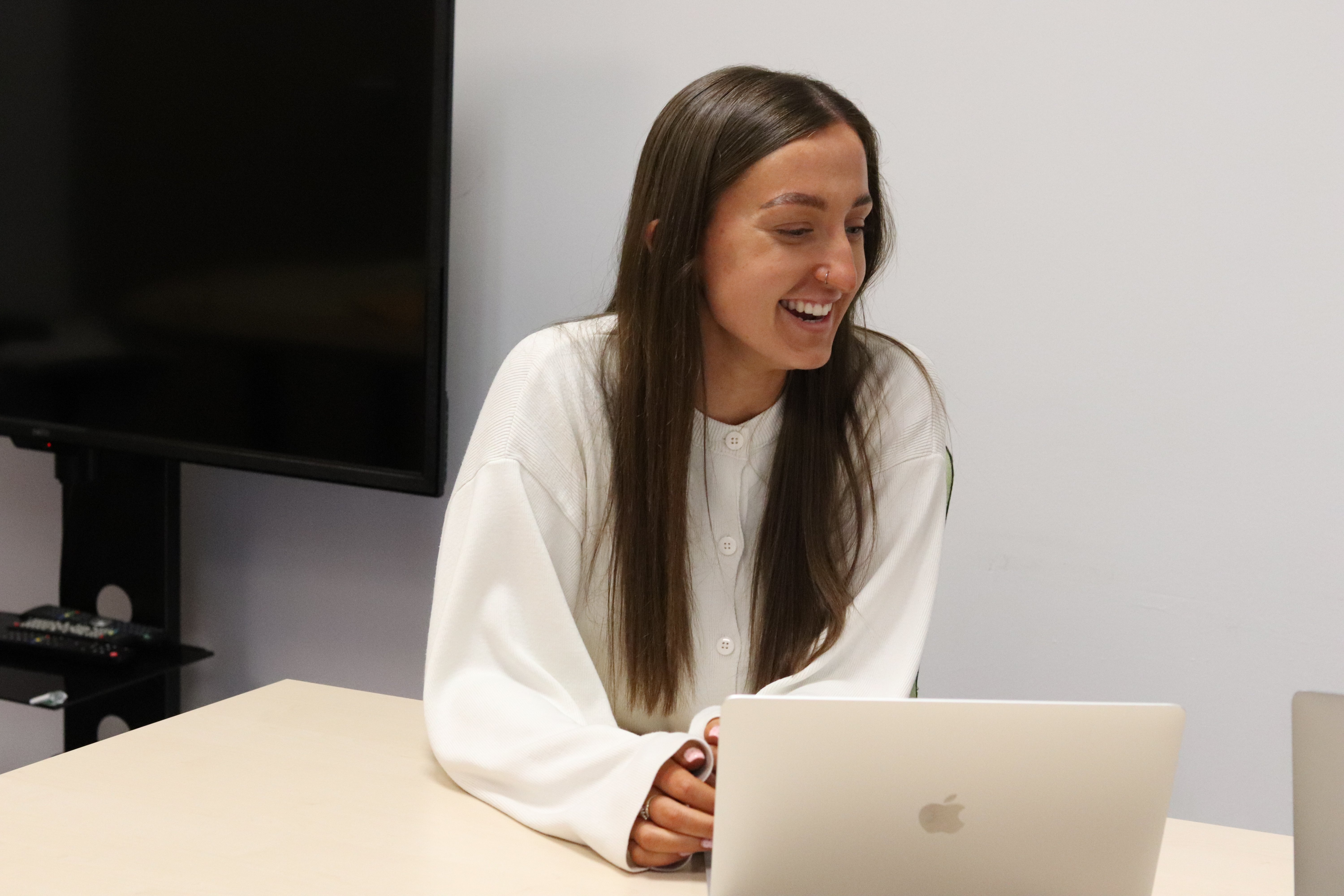 Emily laughing in a meeting with her laptop in front of her, discussing a franchise marketing strategy.