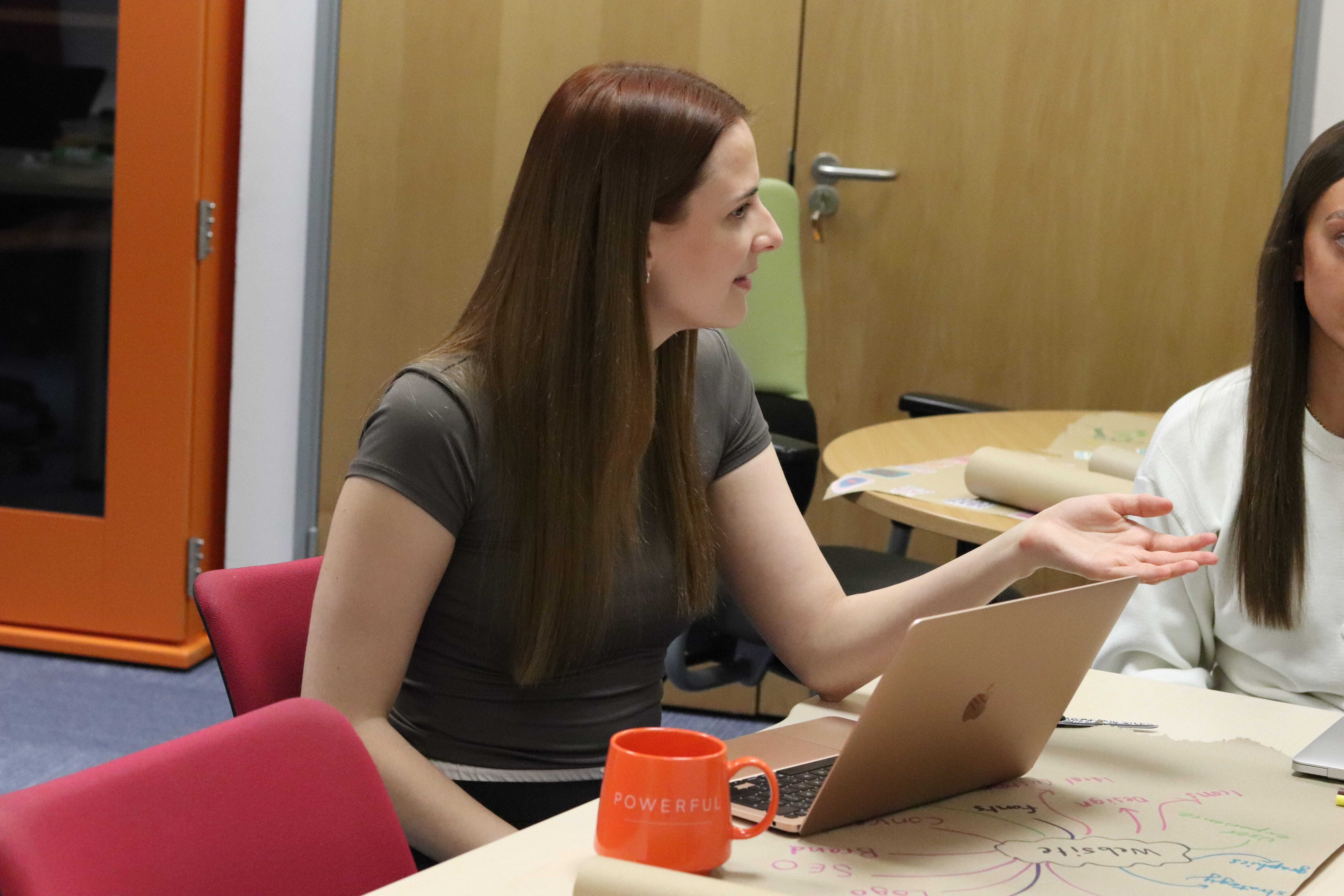 Charlotte in a meeting with a laptop, mug, and website mind map discussing how duplicate content can cost you.
