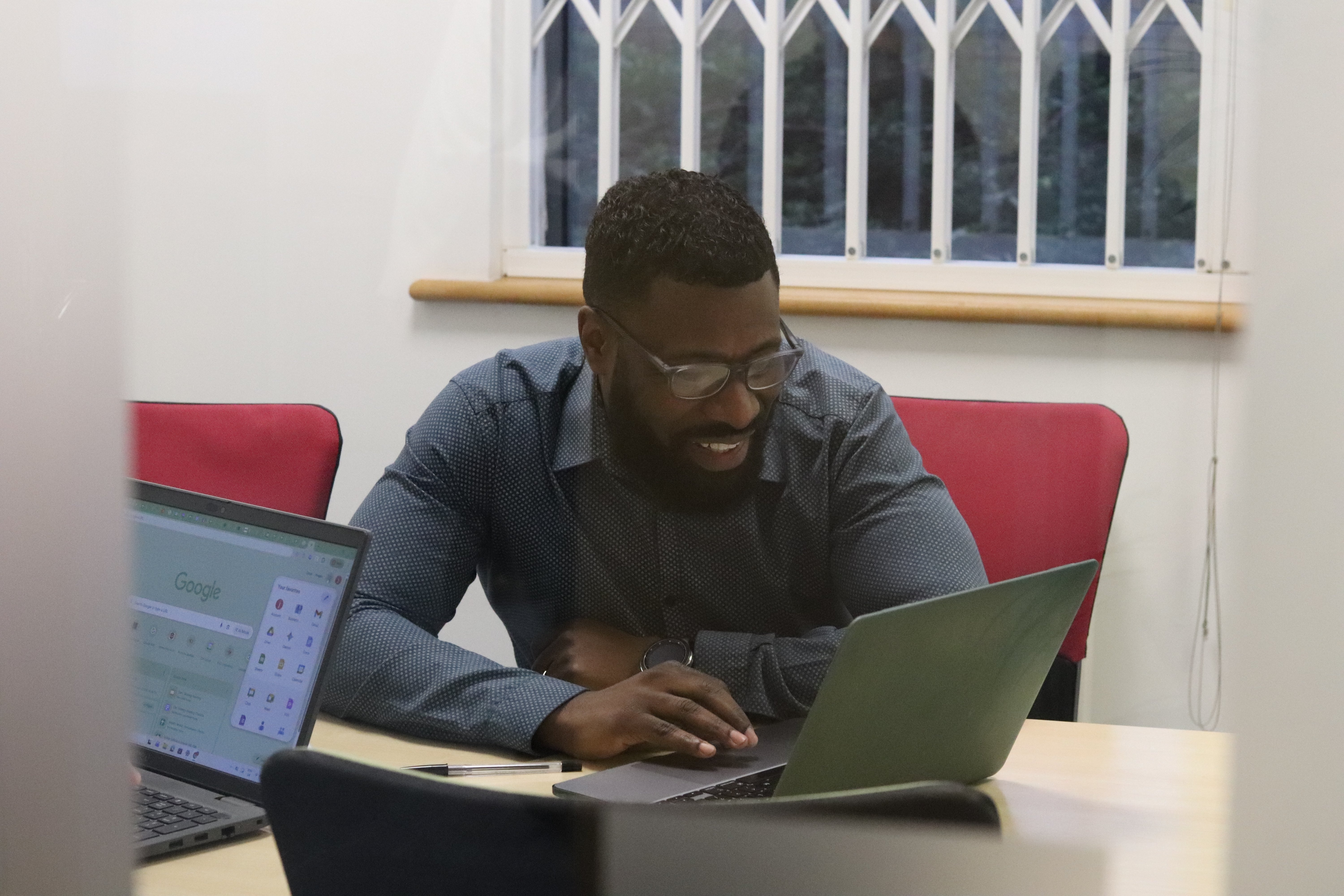 Dan scrolling on his laptop while laughing during a meeting about the cost of SEO.