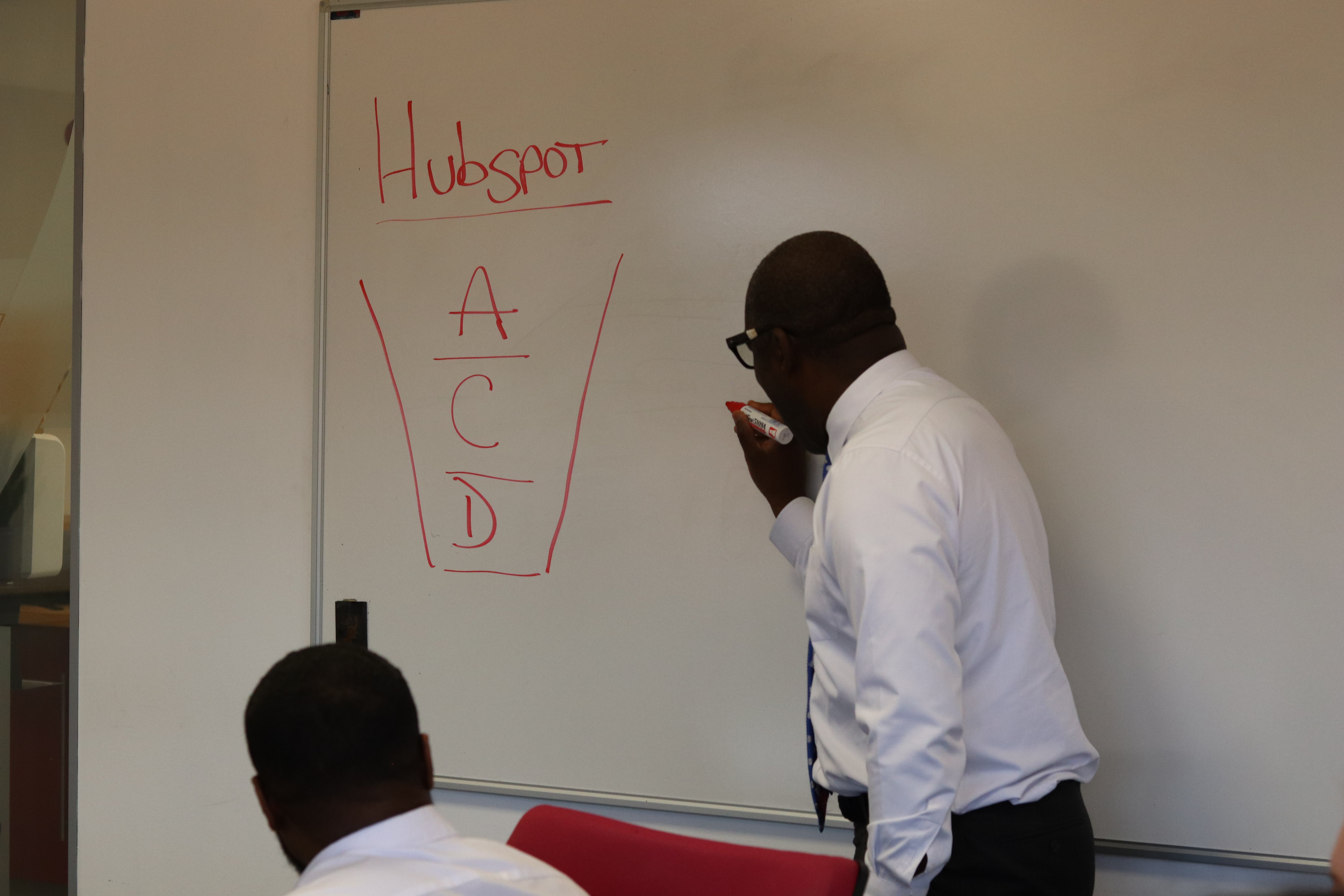 Dave holding a whiteboard pen drawing on a big whiteboard woith the words Hubspot on the board.