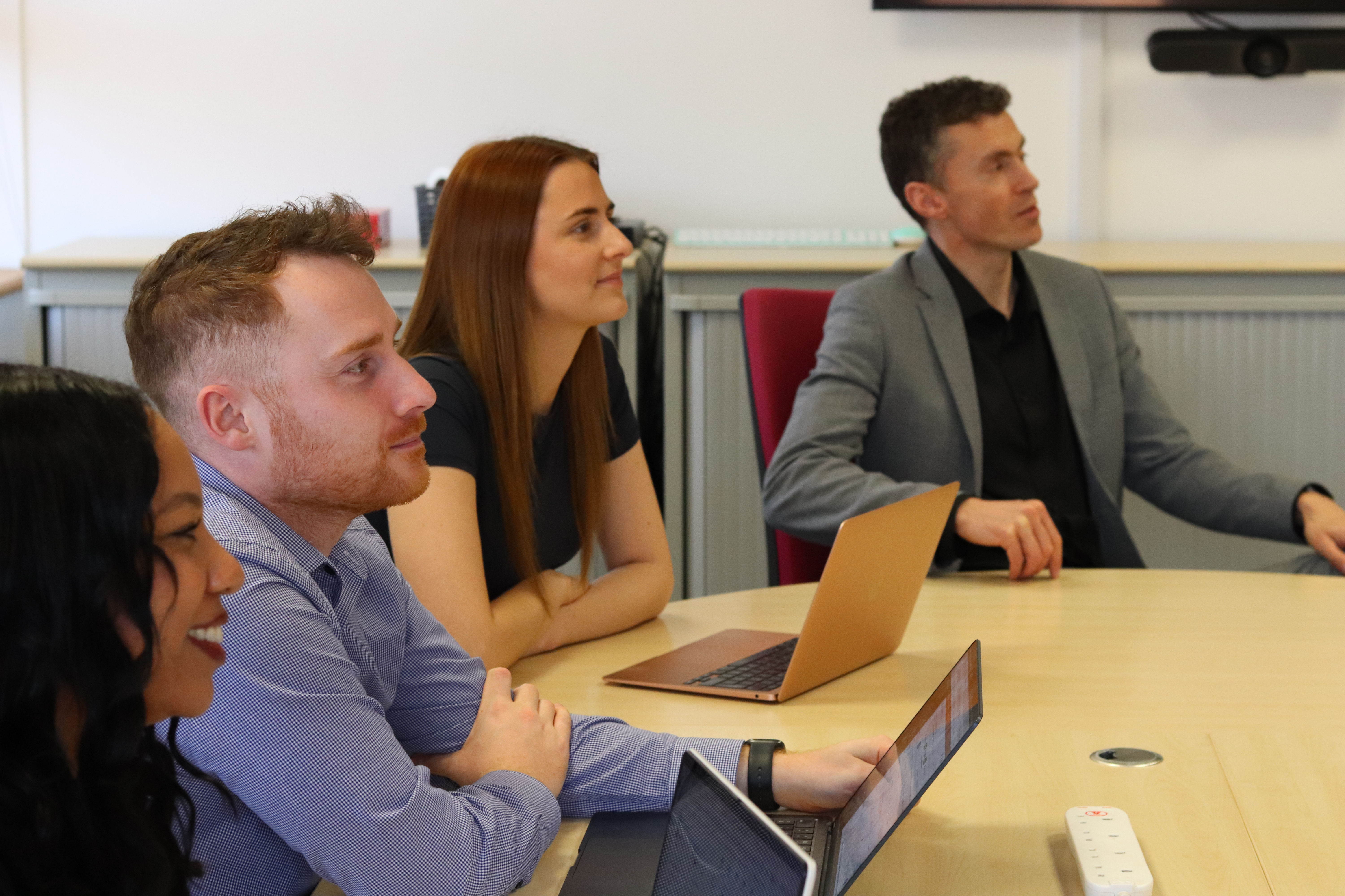 Kerry, John, Charlotte, and Will, all looking the same way and paying attention in a meeting.