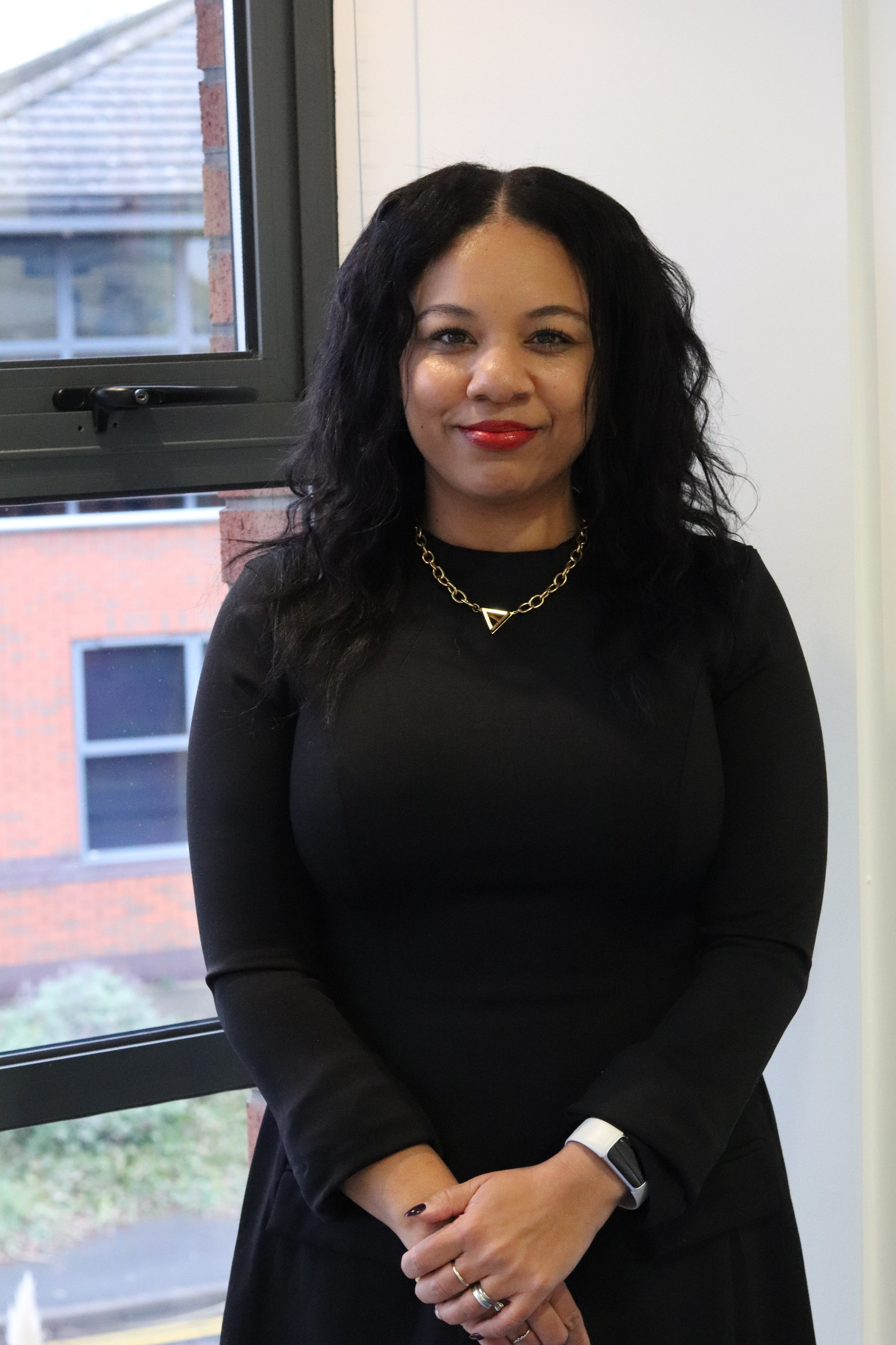 Kerry, who is head of social media at JDR, standing in a black dress smiling at the camera.