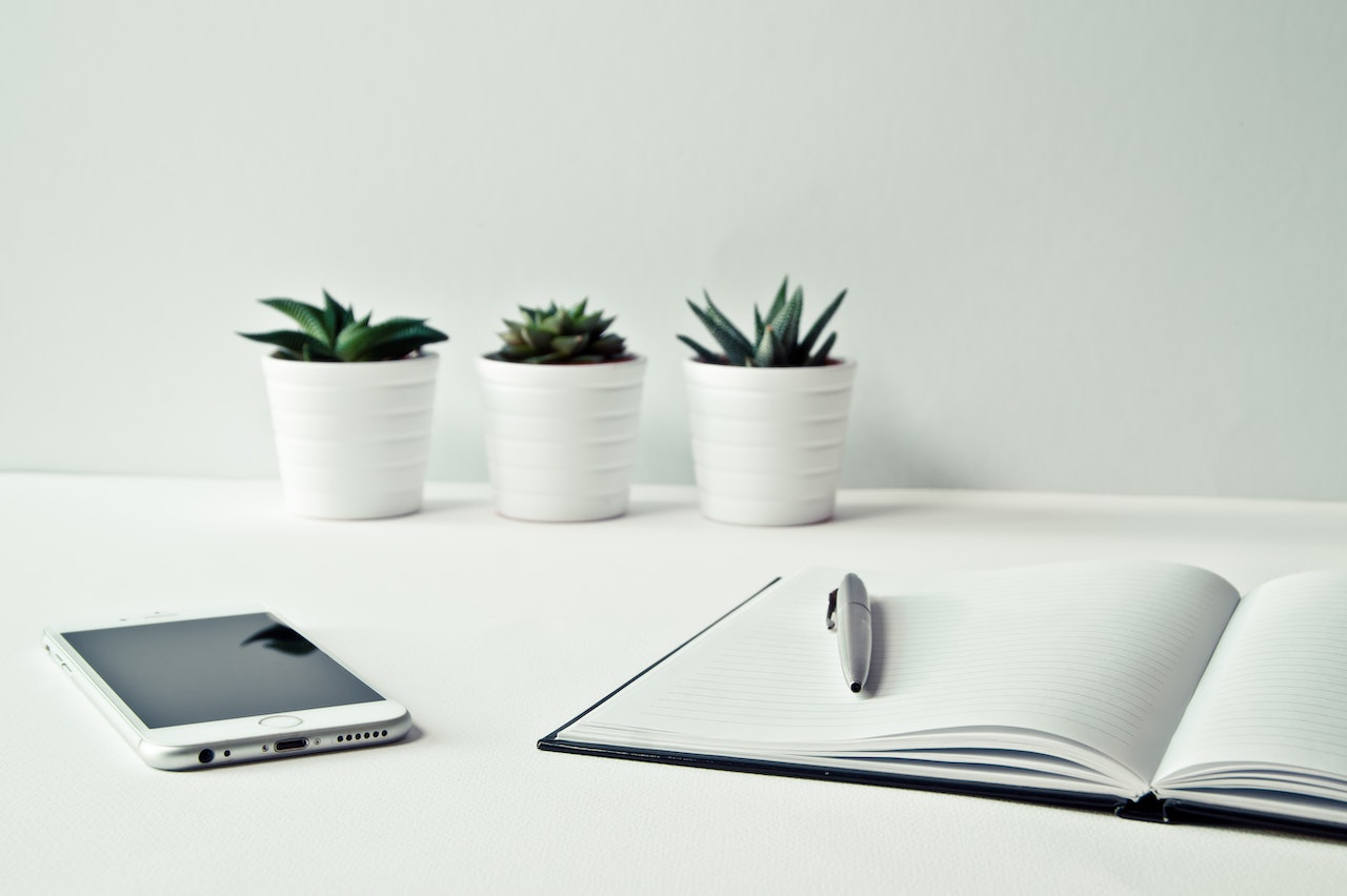 An open notebook next to a smartphone and succulents ready for someone to make a checklist for hiring an B2B Digital Marketing Agency