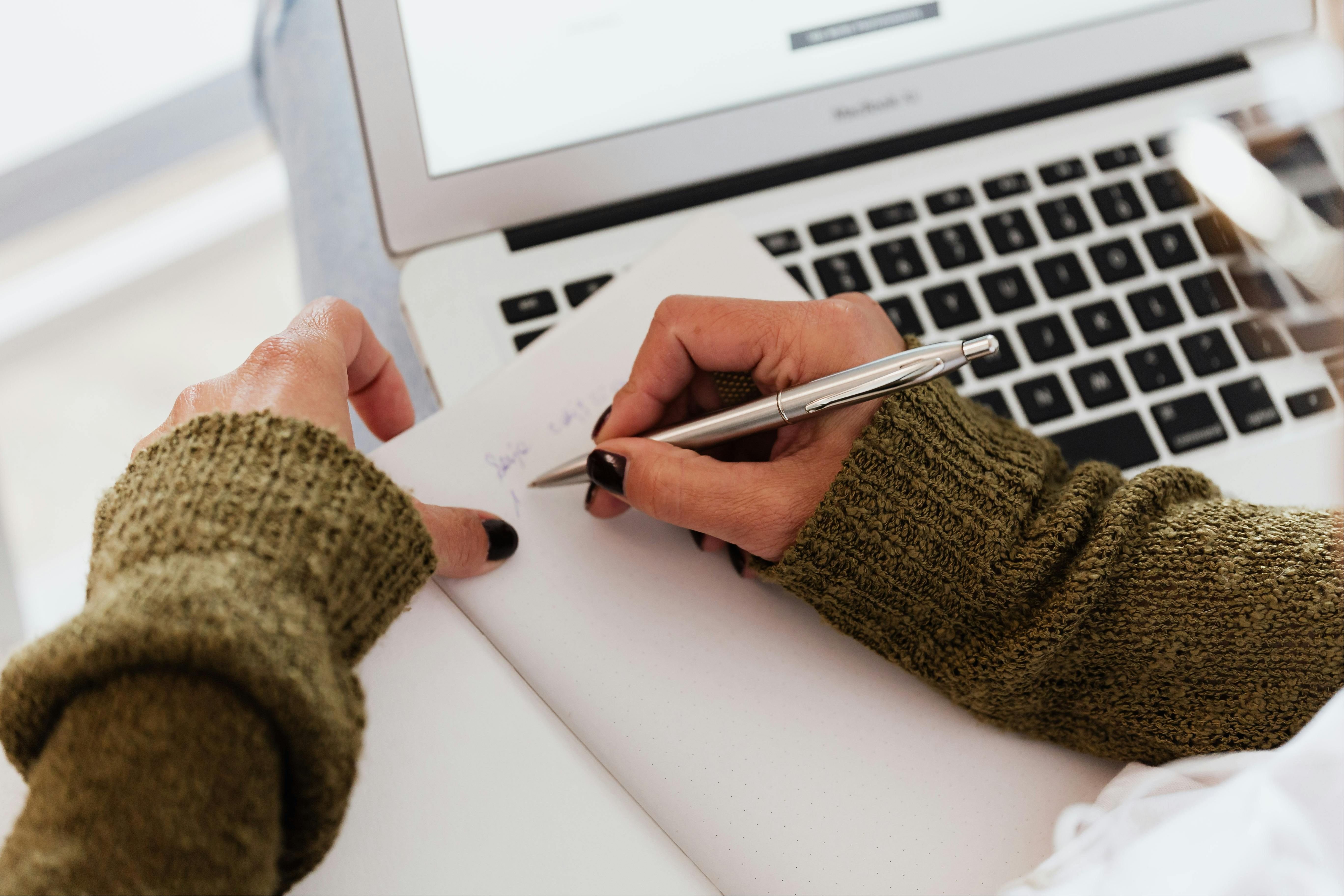 A woman writing down key steps for a smoother exit strategy on a notebook.