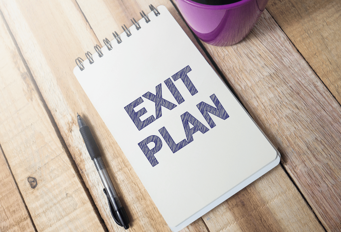 Exit plan written in a notepad next to a pen and a cup of coffee.