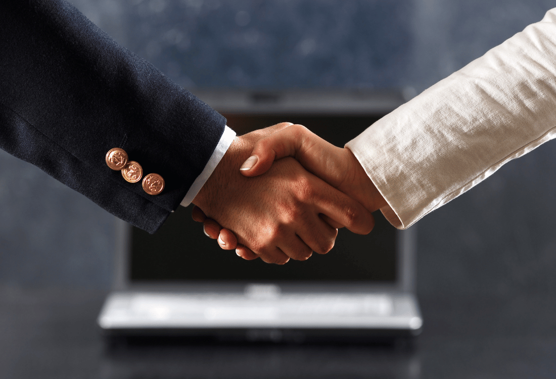 Two people shaking hands to celebrate selling a business.