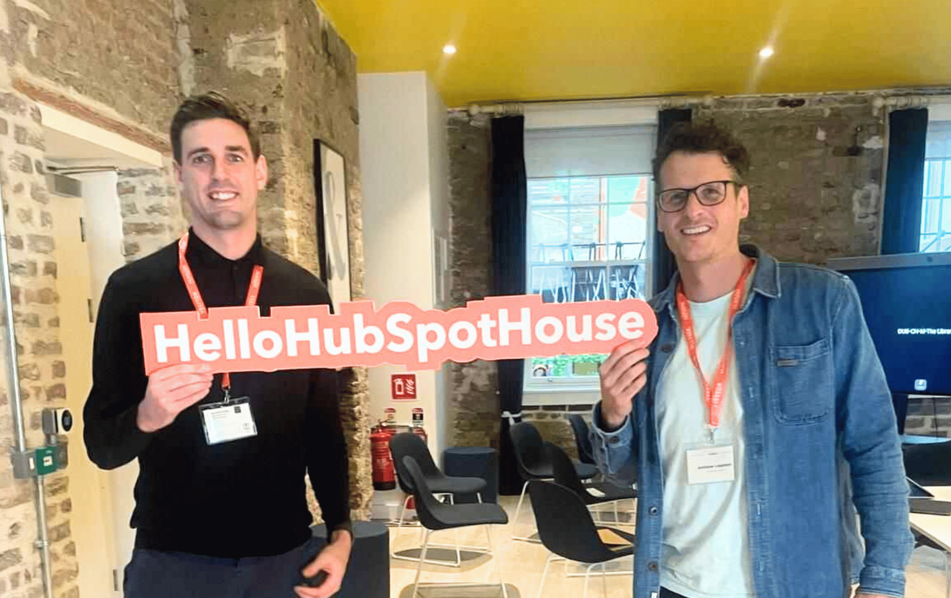Andy Gibbins and Andy Leamon proudly display a Hubspot sign at a Hubspot event. 