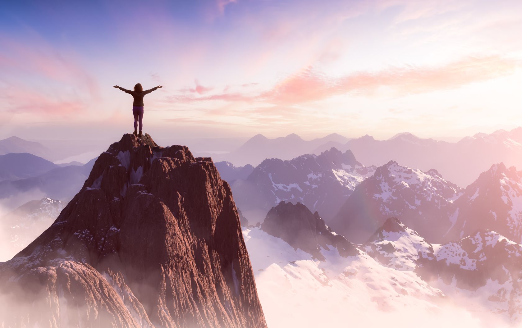 A business woman having scaled many challenges to reach the peak of a mountain overlooking a mountain range at sunrise with her arms out wide, ready to overcome challenges for her business with inbound marketing.