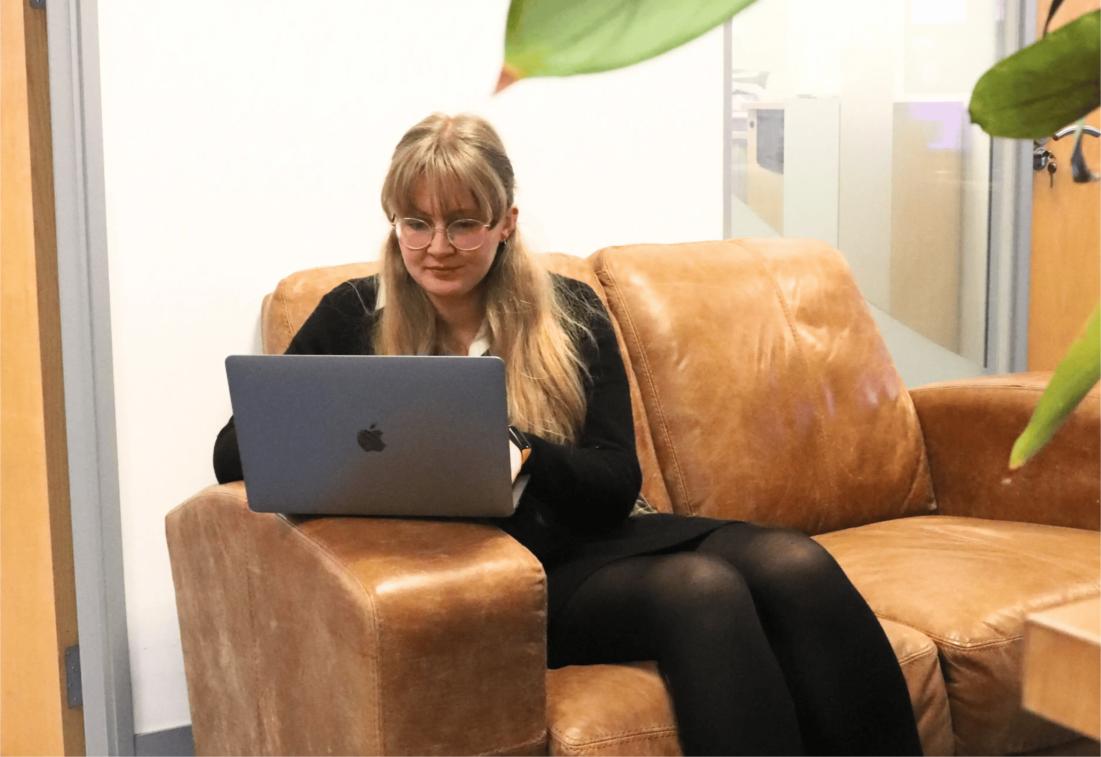 Emma sat on the office sofa using a laptop