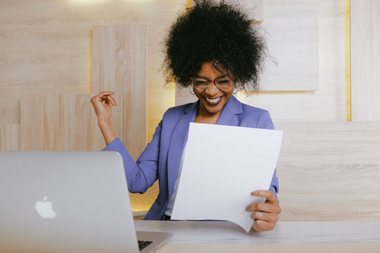 A business woman cheering as she reads her latest revenue report which have increased after taking on new proven strategies