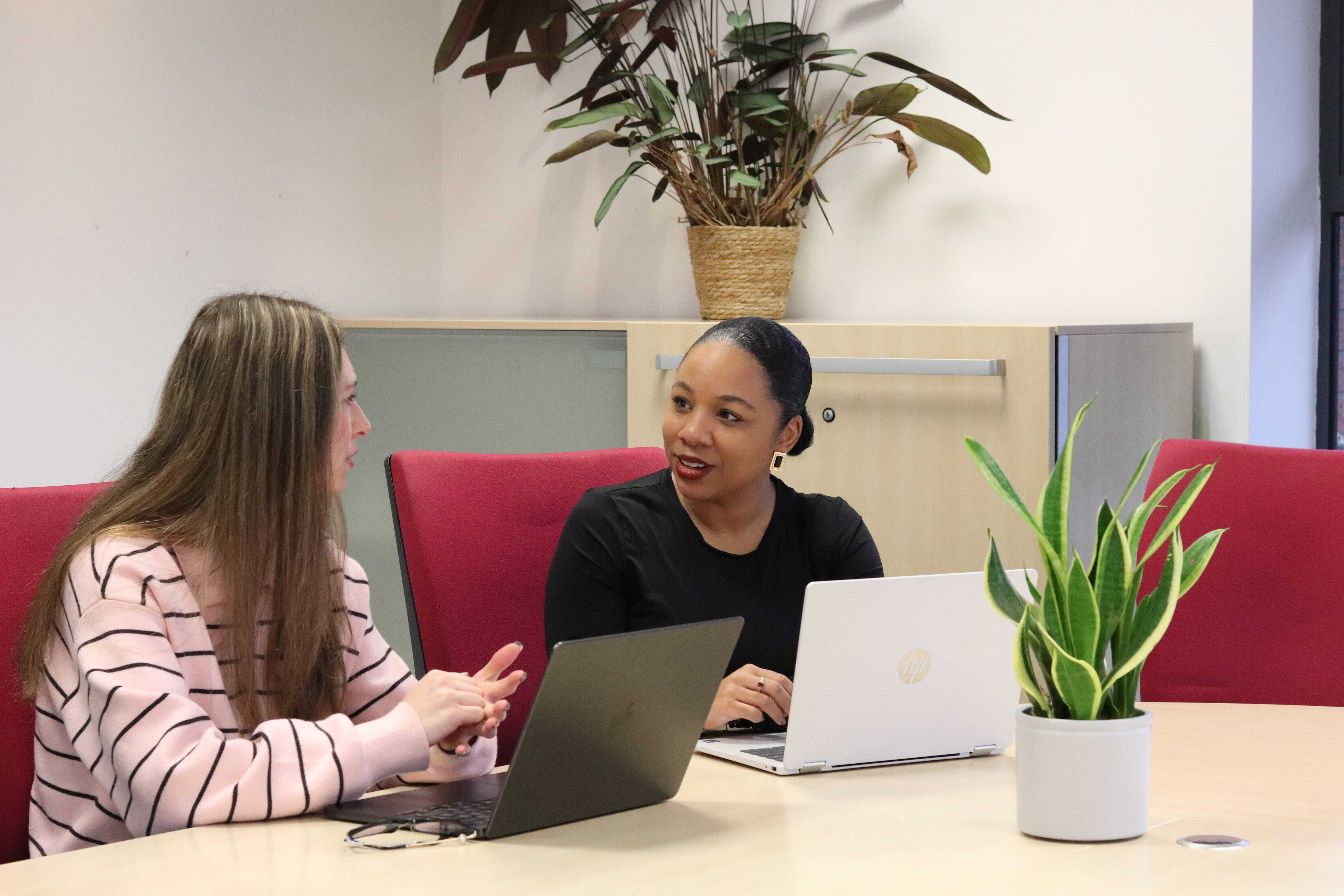 Sophie and Kerry at a meeting table with their laptops discussing how to optimise for AI bots, social search, and human buyers.