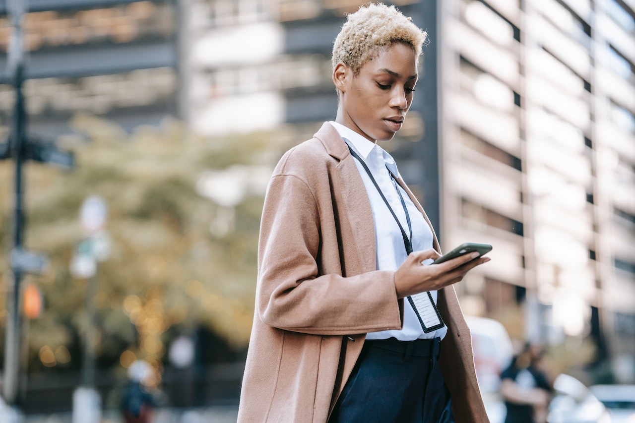 A business woman outside of her place of work using LinkedIn on her phone to get more leads effectively