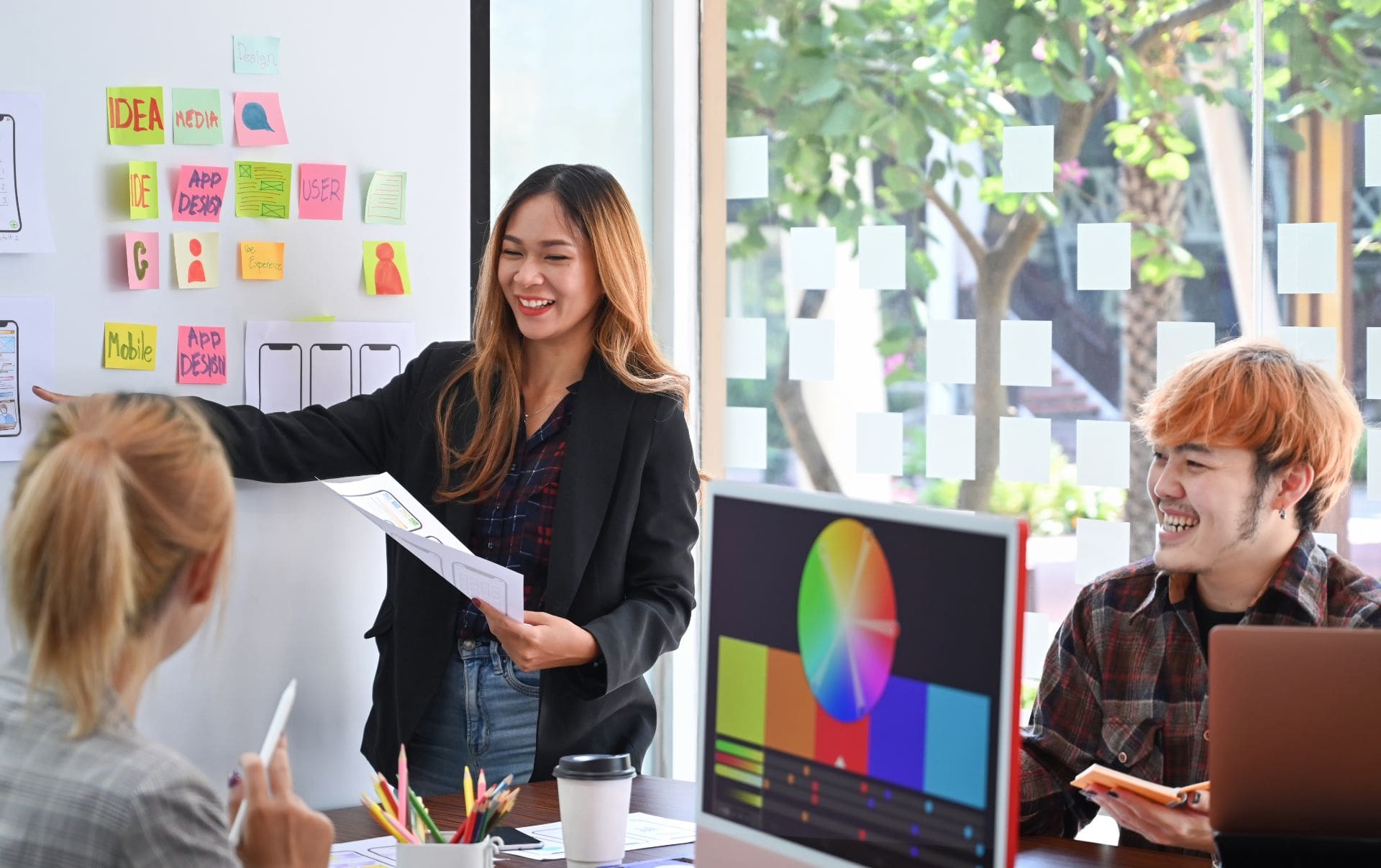 Three members of the website team in an Ecommerce business working on the colour pattern for their new website excitedly smiling after switching from a WooCommerce WordPress website to a Shopify website.