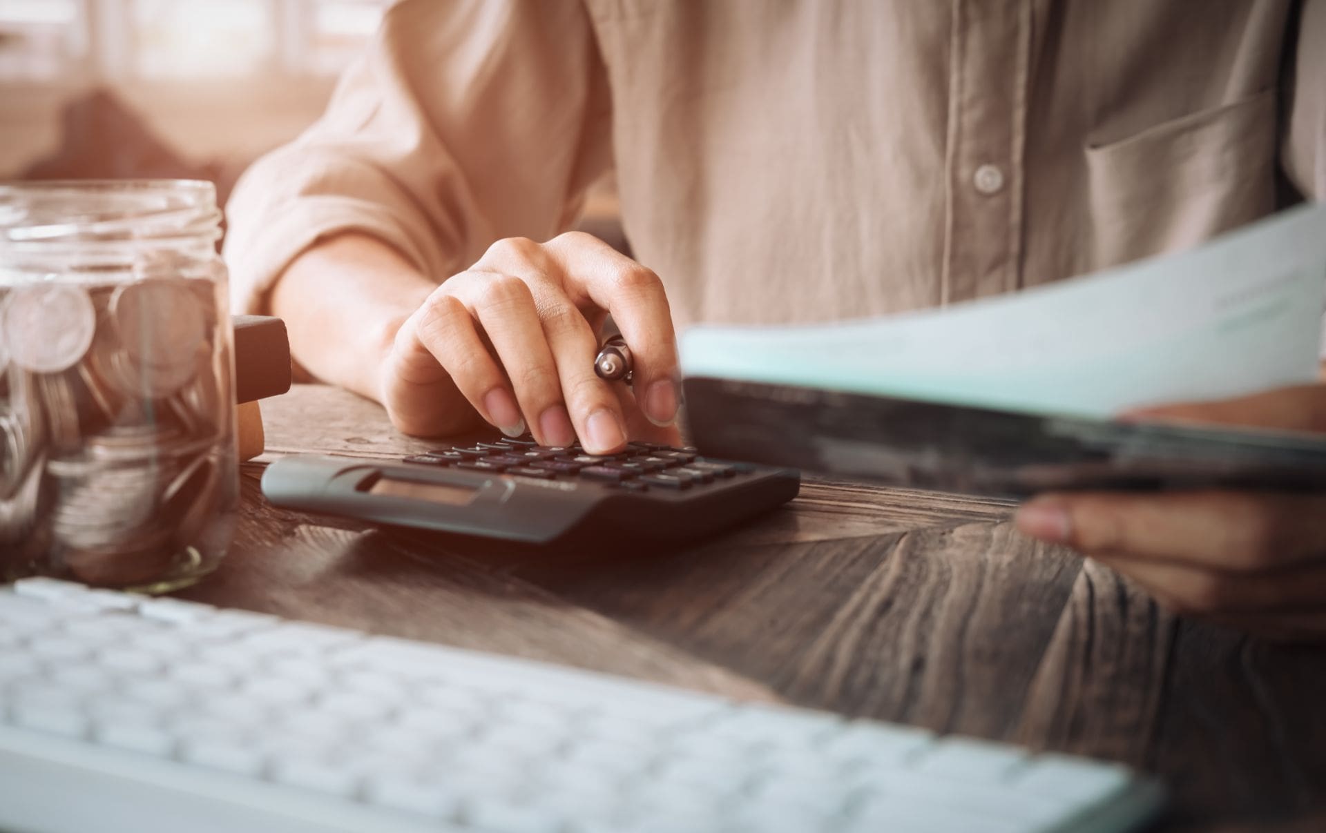 A business owner at her desk with a datasheet and calculator as she calculates her budget for a new website.