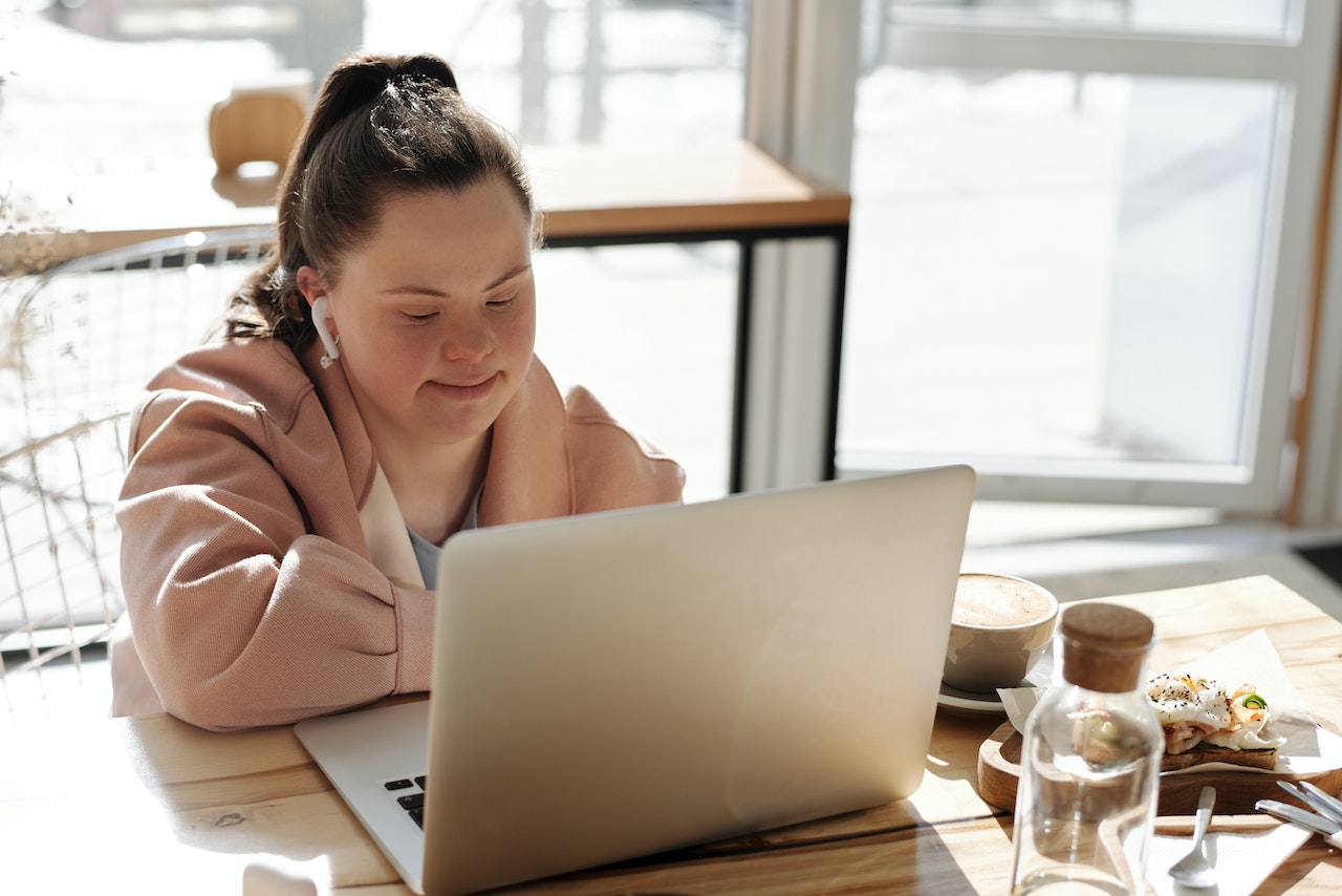 A businesswoman with down's syndrome working at her laptop, using a screen reader to read the website of an accessible website