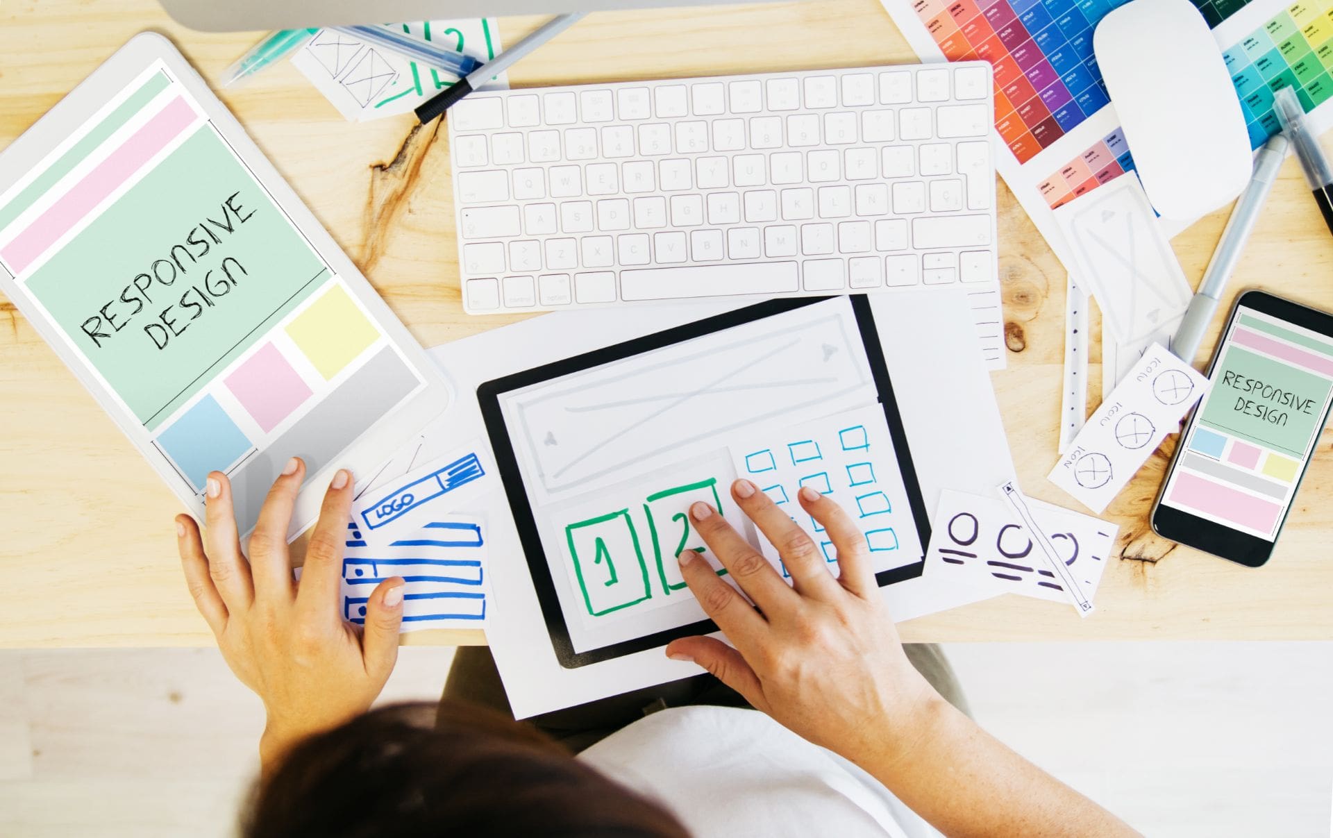 A business woman sitting at her desk with website mock-ups on several pieces of paper as she tries to design a new website for her business in budget.