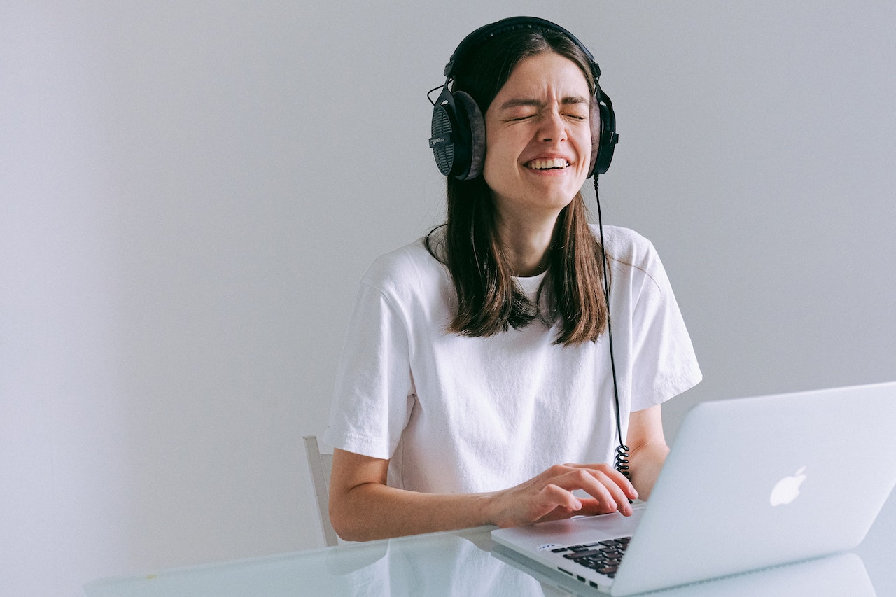 A woman on her laptop with headphones on listening to her screen reader which is perfectly reading a well optimised and accessible website