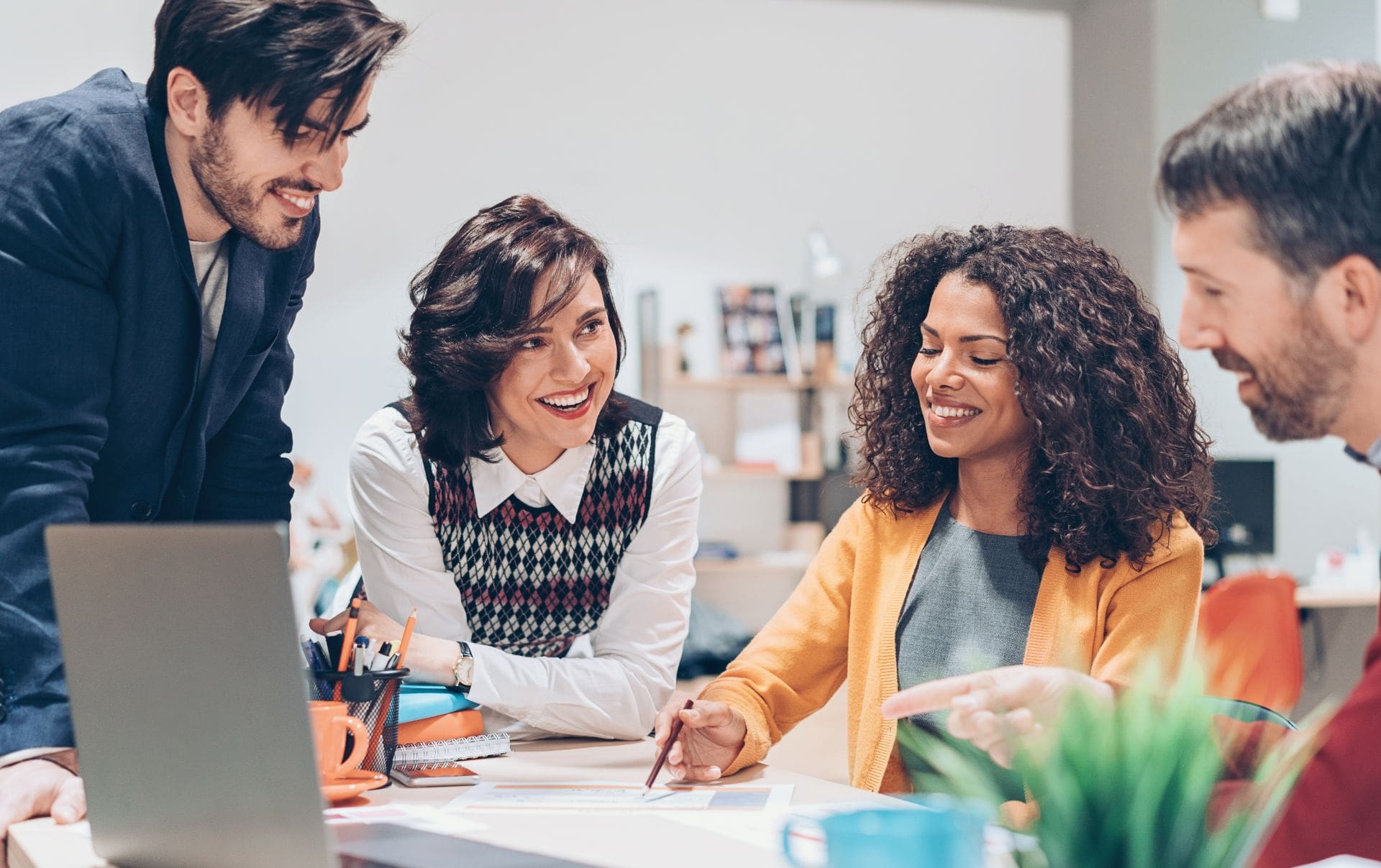 A small business owner sitting at a desk with three members of an Elite HubSpot Agency as they discuss what they can do help benefit the business.