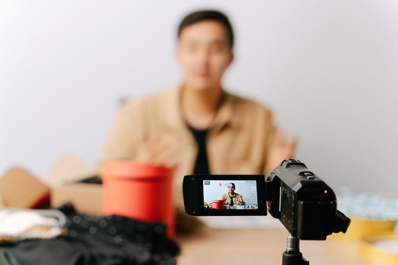 A man sitting in front of a video camera creating video marketing content