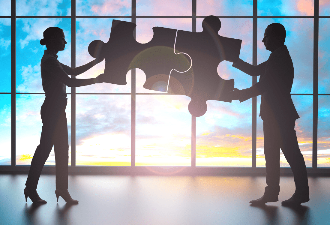 Two business professionals collaborating to connect puzzle pieces, symbolising the partnership and strategic alignment between small businesses and an Elite HubSpot Partner.