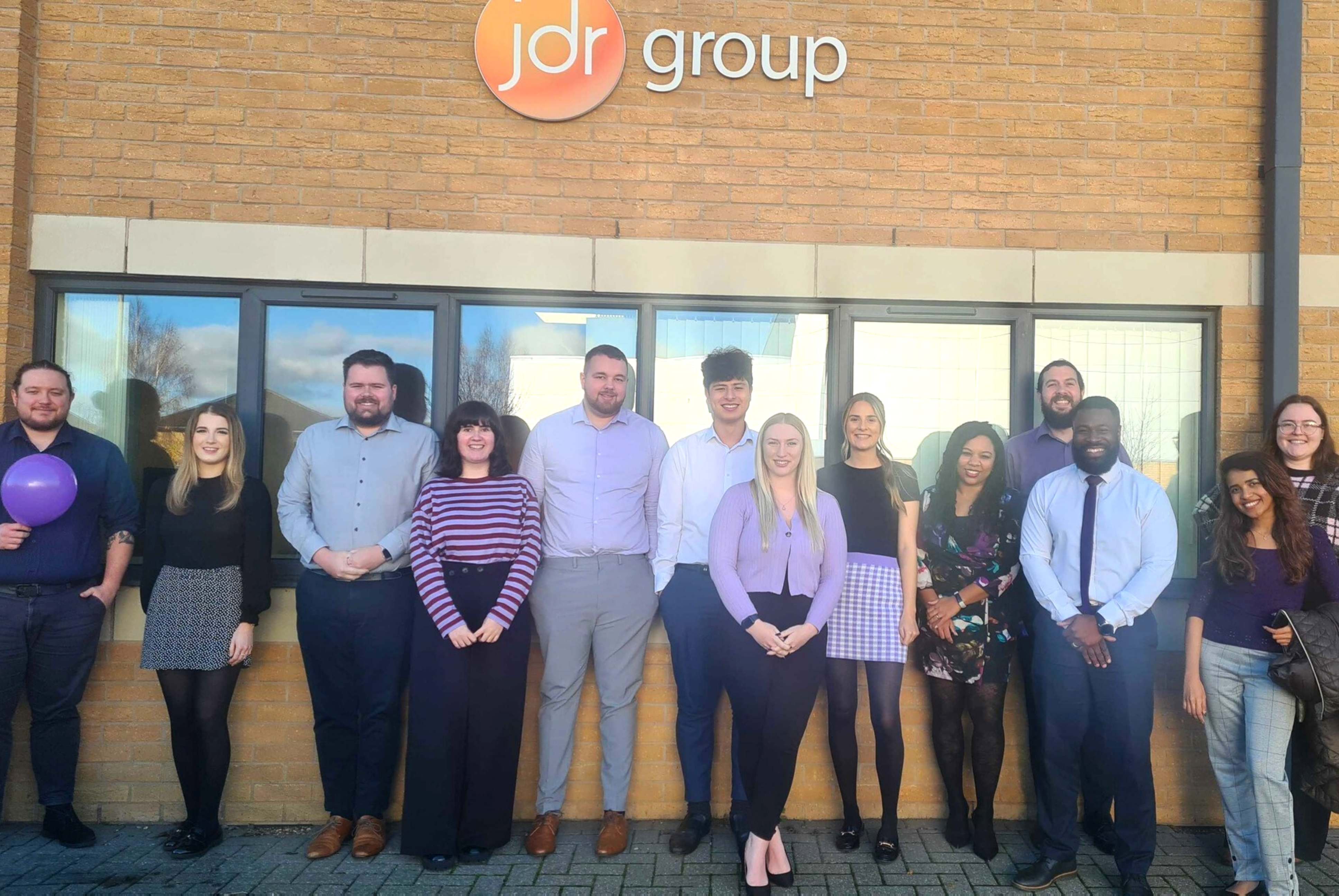 The JDR team standing outside of the office together, smiling