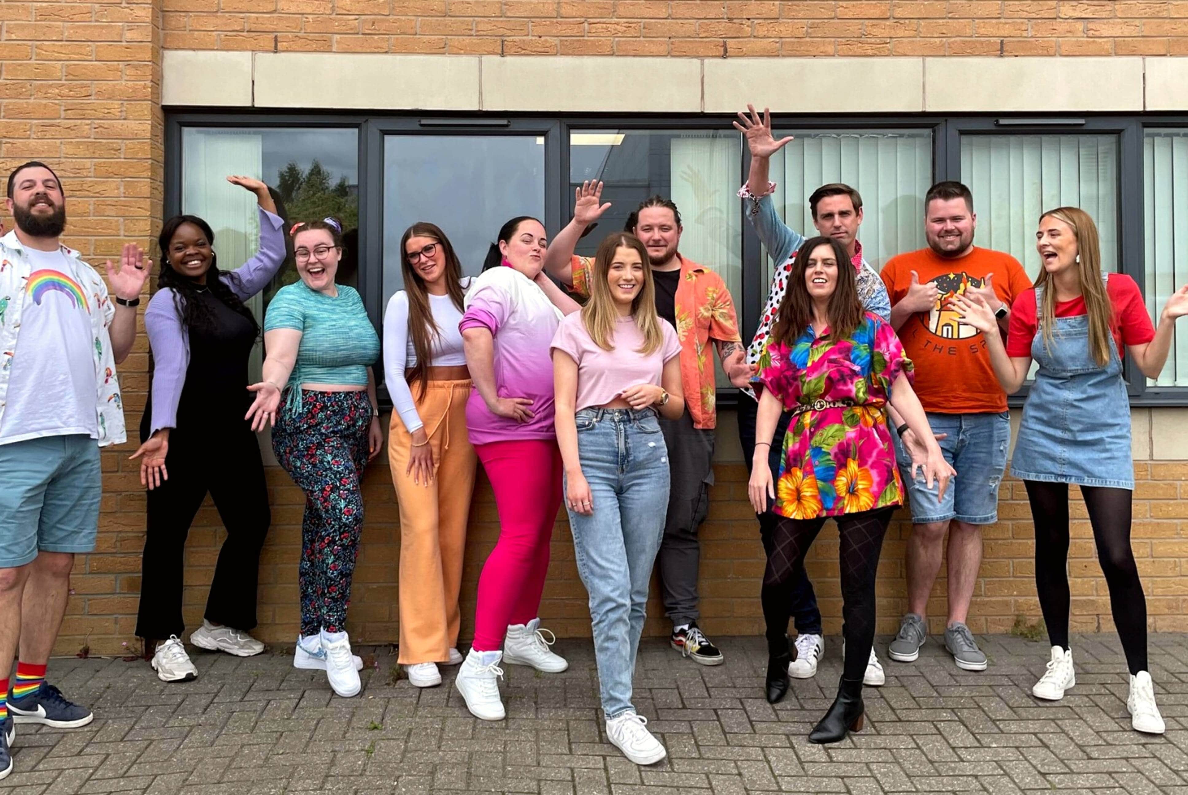 the JDR team posing gleefully, wearing an assortment of colourful clothing, celebrating pride month on the office's pride day