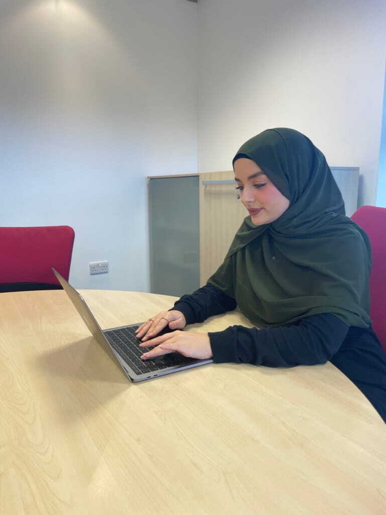 Nidia typing on her laptop at a desk, working on law firm marketing strategies.