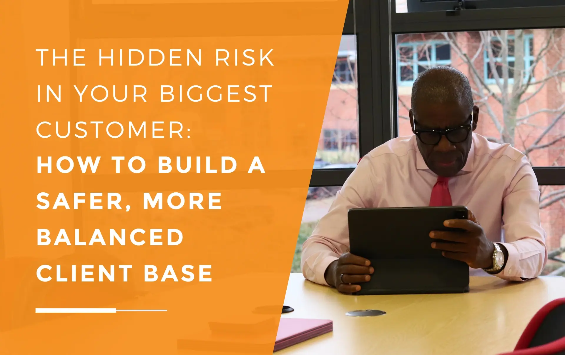 JDR Group’s managing director sitting at a meeting table, focused on working on a tablet, with office buildings visible through the window behind him.